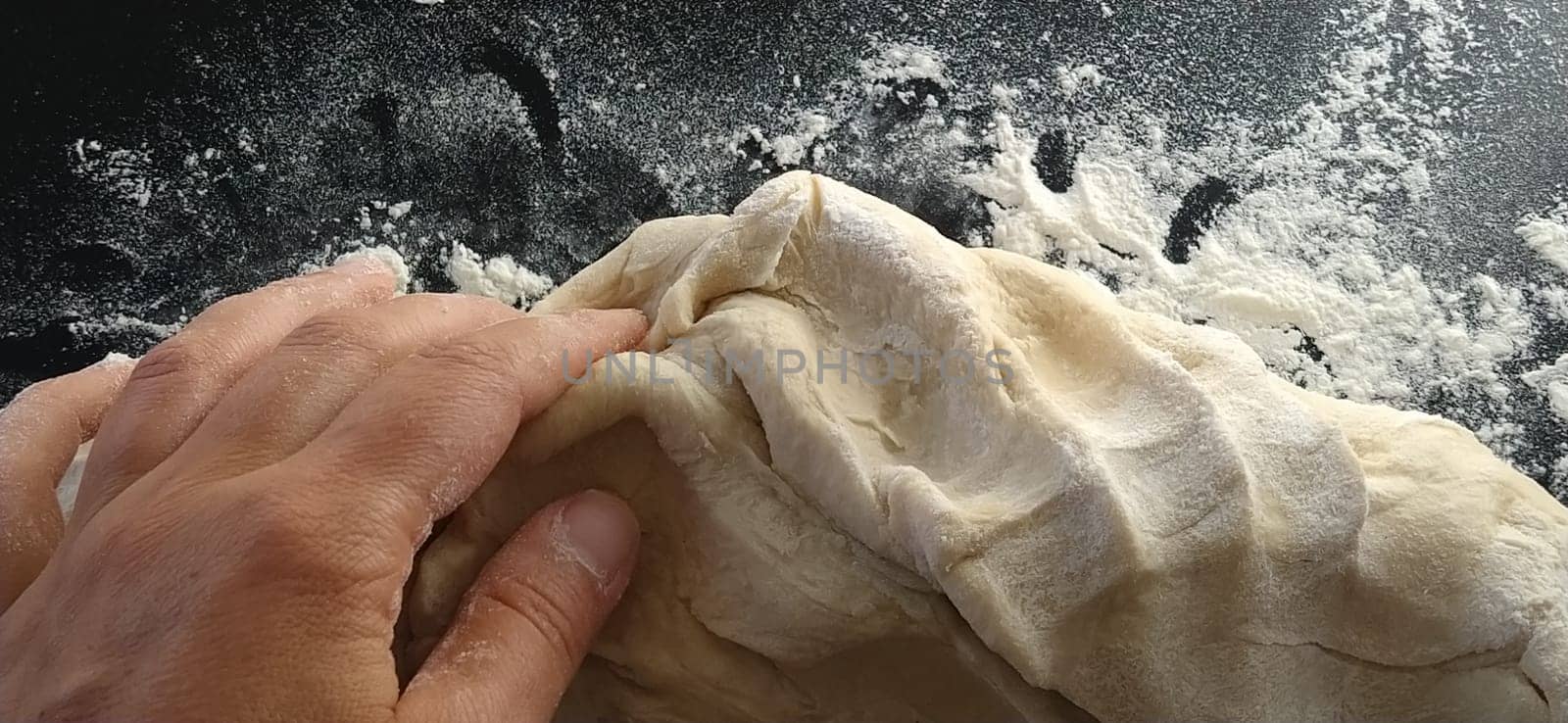 Hands knead the dough. The woman kneaded dough for baking or dumplings. Preparation of flour, water and egg mass for thermal processing. Chef hands.