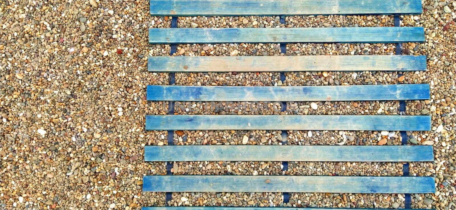 wooden boardwalk on the sand. wooden walkway on the beach. Sticks and planks on the stony ground. Heel protection from damage. Summer time and recreation at sea or ocean
