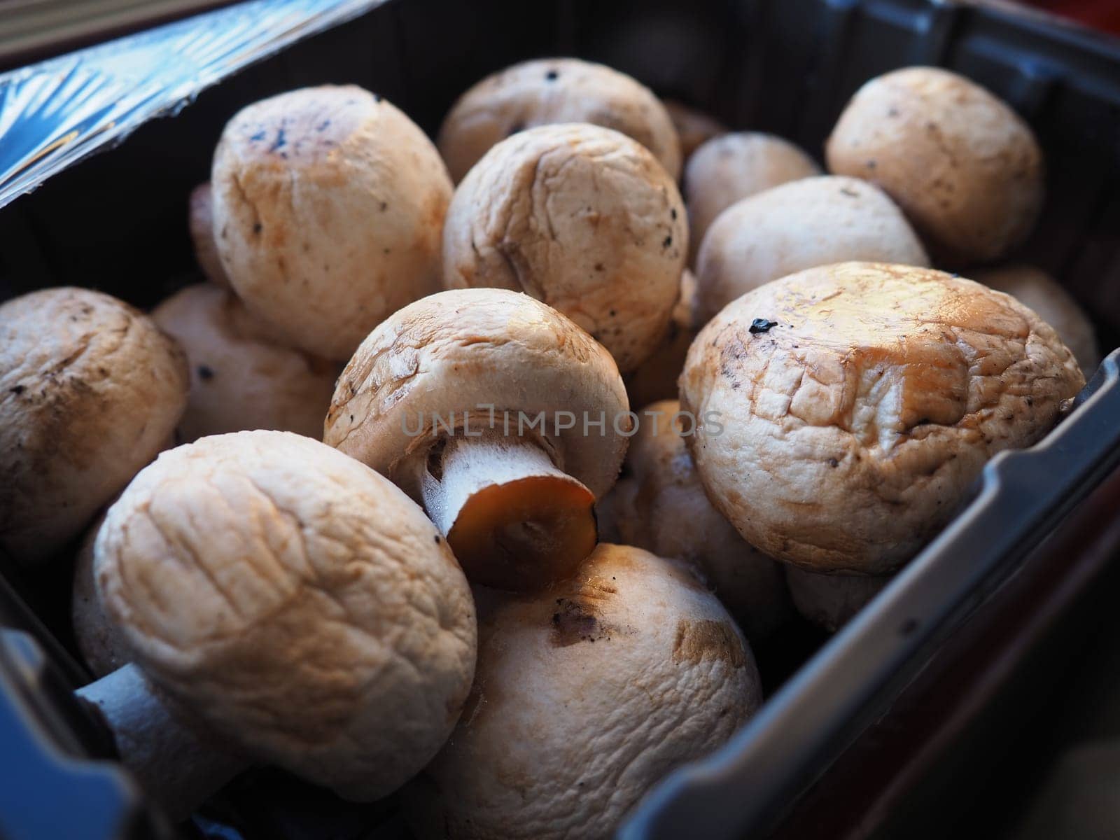 champignons in black plastic packaging. Brown champignons grown in a mushroom factory. Mushrooms in an opened store packaging. Close-up of mushrooms after defrosting. Shelf life of food
