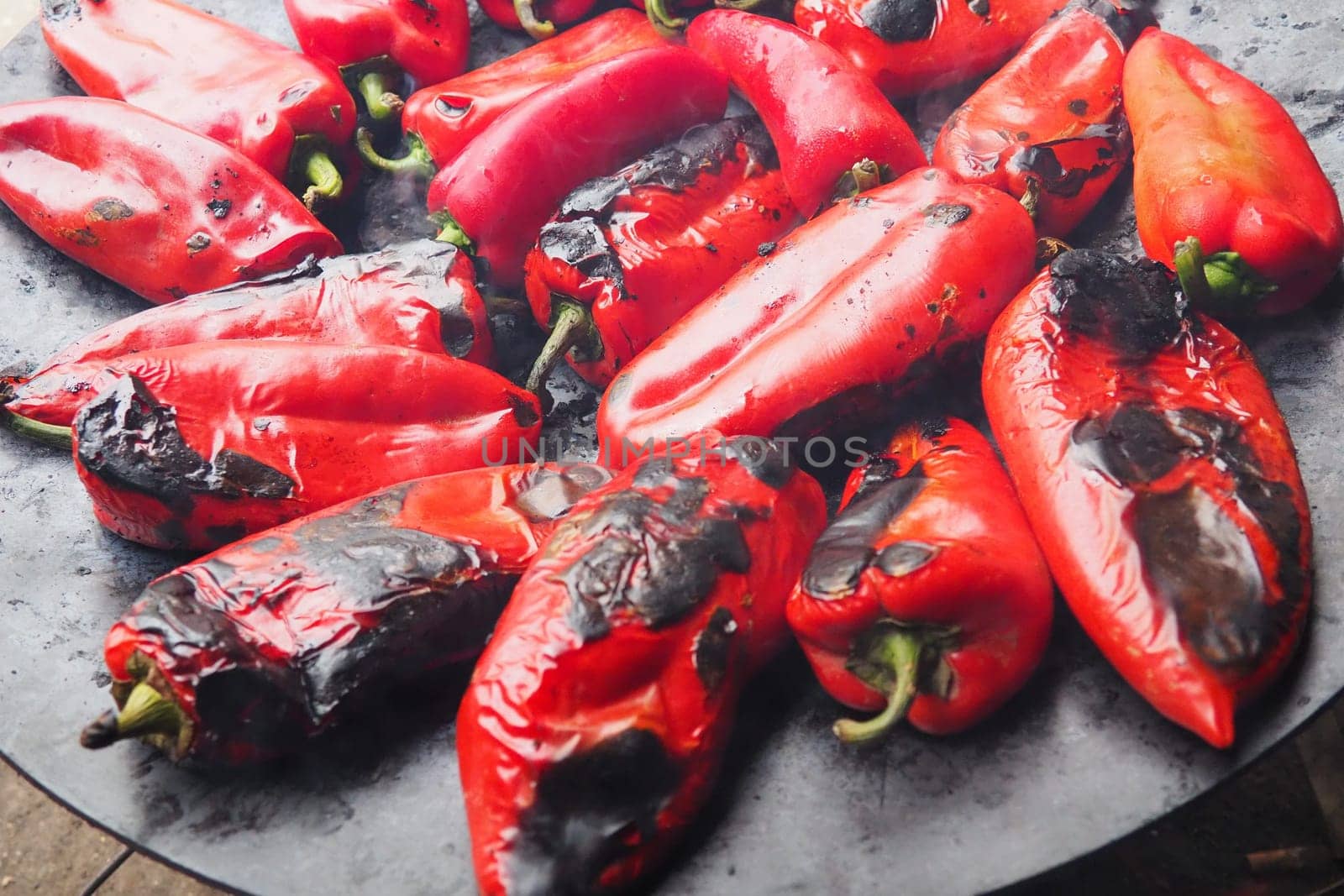 Roasting delicious red peppers for a smoky flavor and quick peeling. Balkan salad recipes. Thermal processing of the pepper crop on a metal circle. Peppers are laid out on a flat baking sheet close-up