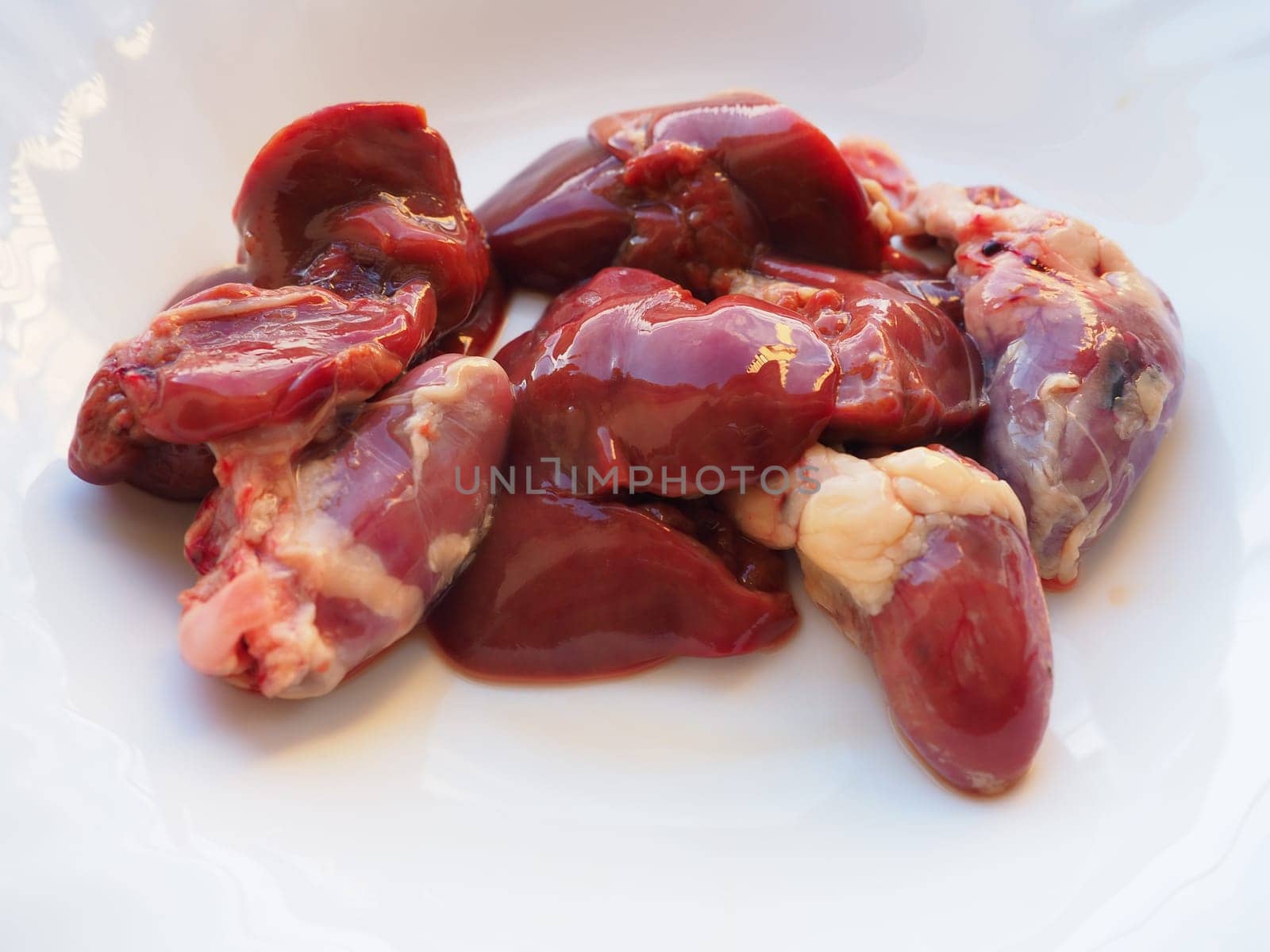raw chicken liver, kidneys and heart. Poultry entrails and offal, prepared for cooking. A diet high in heme iron against anemia. Meat on white background.