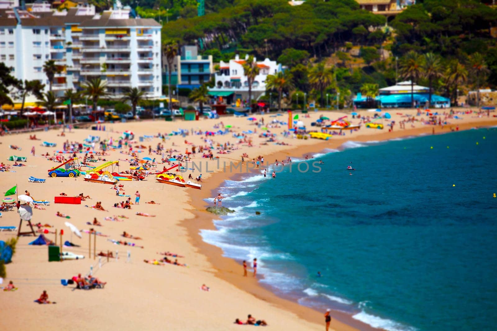 seaside resort, sandy beach, people sunbathing rest tilt shift