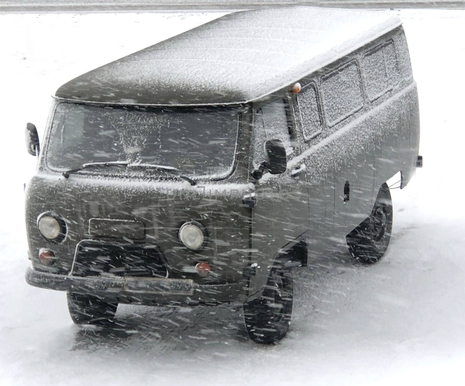 green military car in the snow in a blizzard