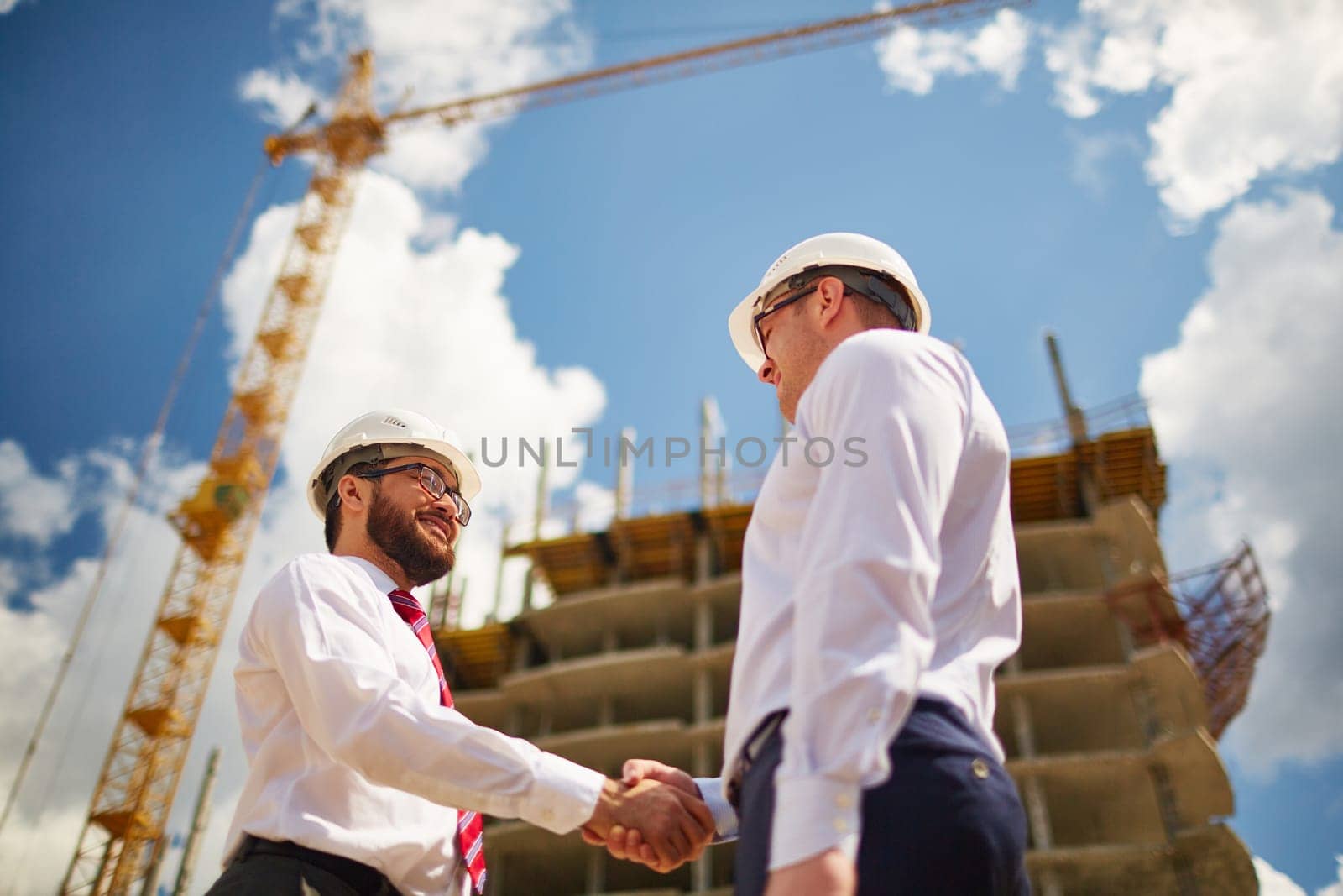 Two businessmen making agreement on background of new construction