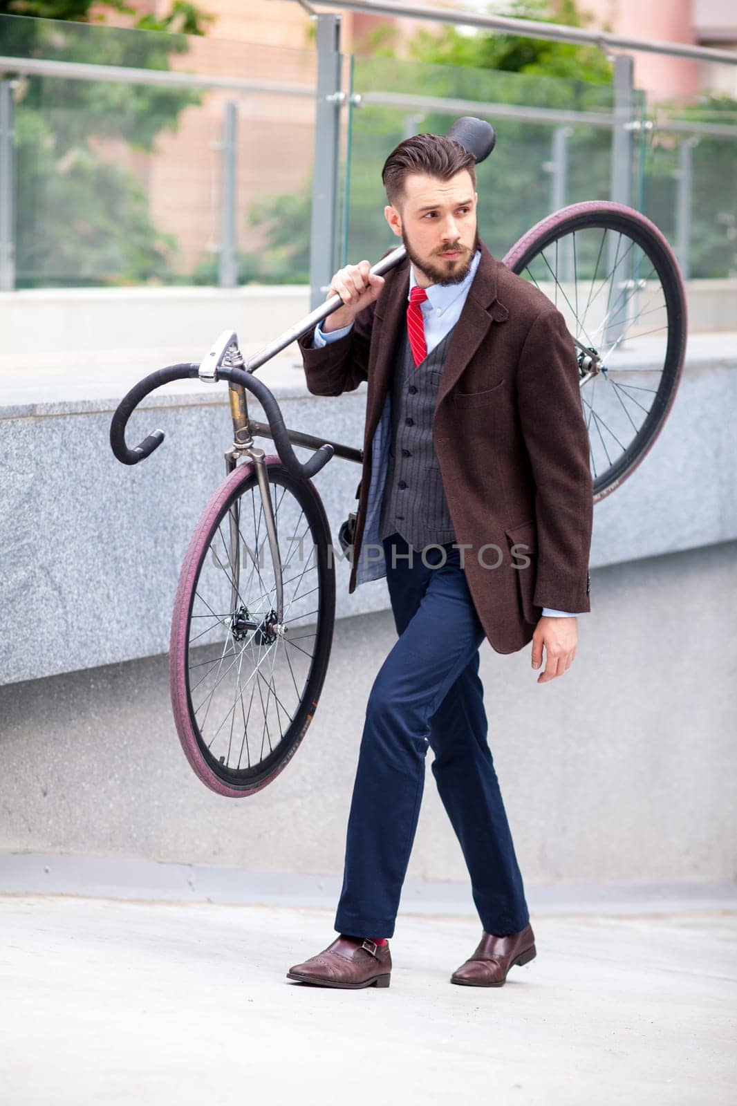 Handsome businessman carrying his bicycle on city streets. The concept of the modern lifestyle of young men