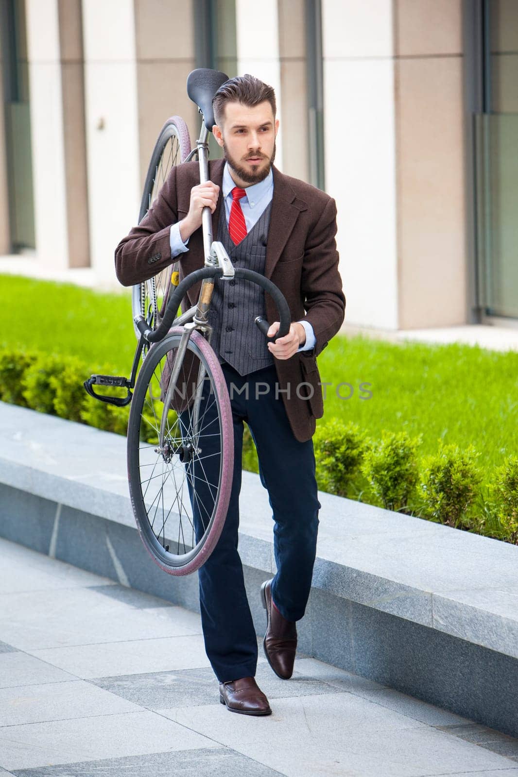Handsome businessman carrying his bicycle on city streets. The concept of the modern lifestyle of young men