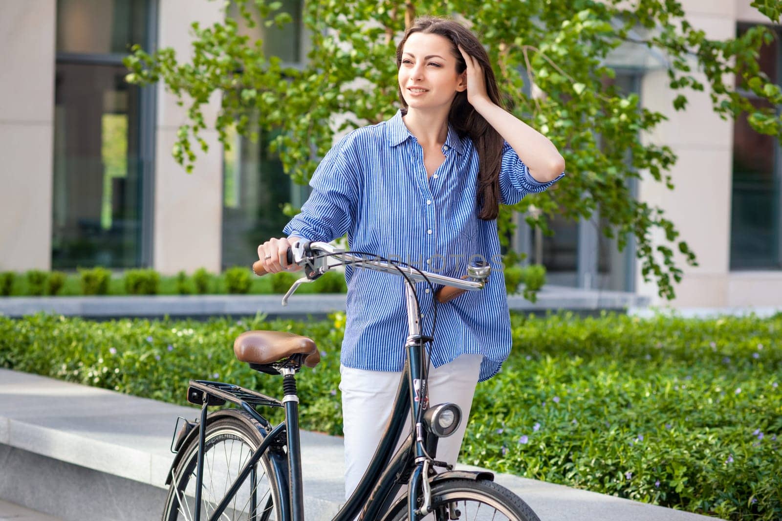 Pretty girl iin blue shirt with a bicycle at street