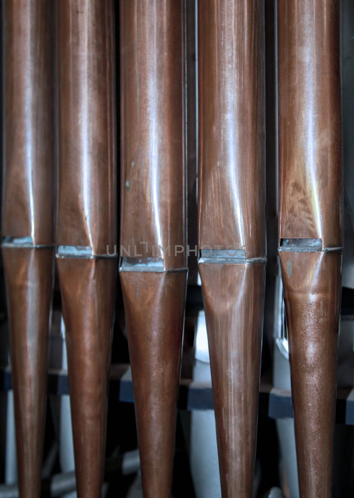 Many organ pipes stand side by side in an organ over a bellows.