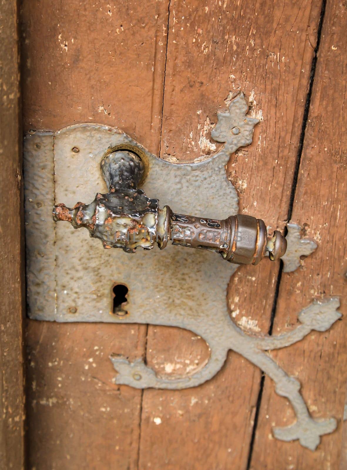 An old lock with an antique door handle. A wooden door with an old lock.