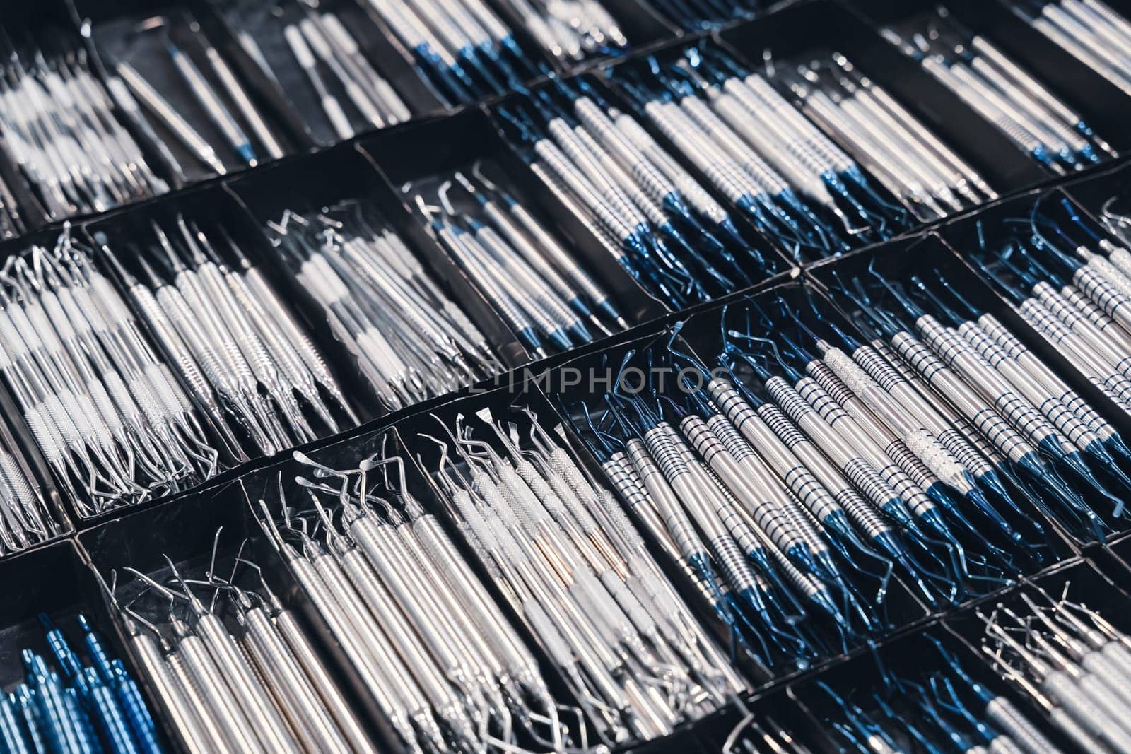 top view closeup of row of many basic stainless steel dental tools supplies on display in medical boxes