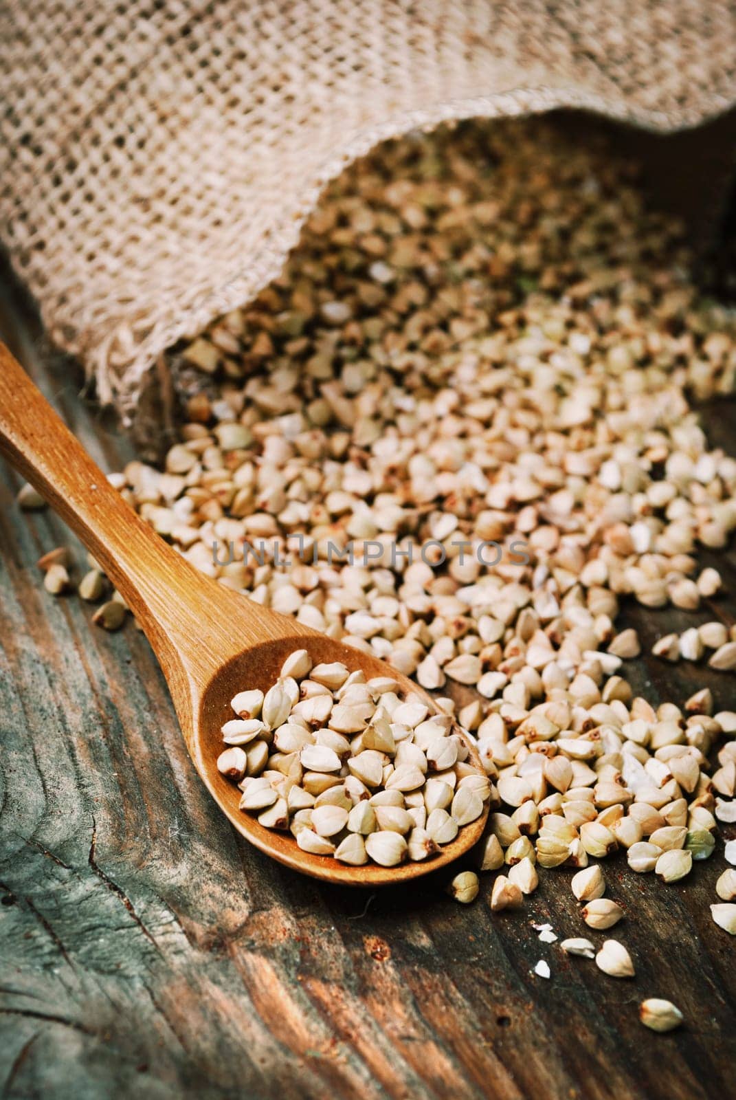 Still life  with buckwheat grain heap in wooden spoon on vintage wooden table background. Organic healthy eating cuisine. Vegan gluten free buckwheat cereal diet.