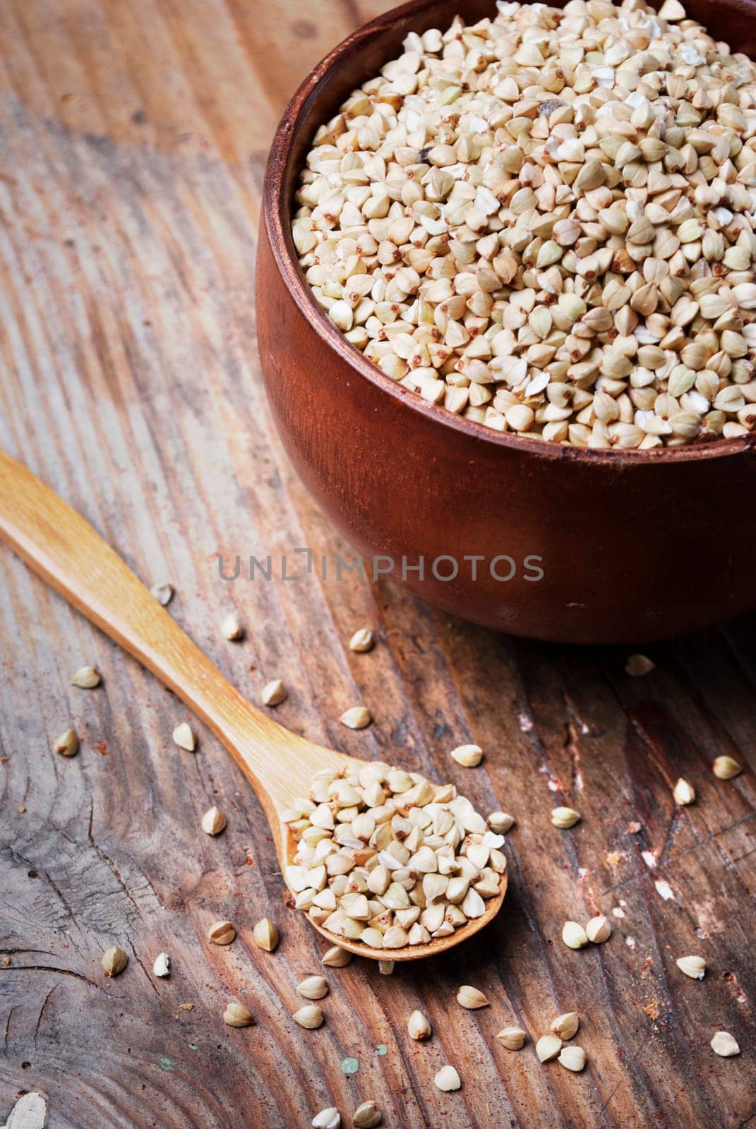 Still life  with buckwheat grain heap in wooden bowl on vintage wooden table background. Organic healthy eating cuisine. Vegan gluten free buckwheat cereal diet.