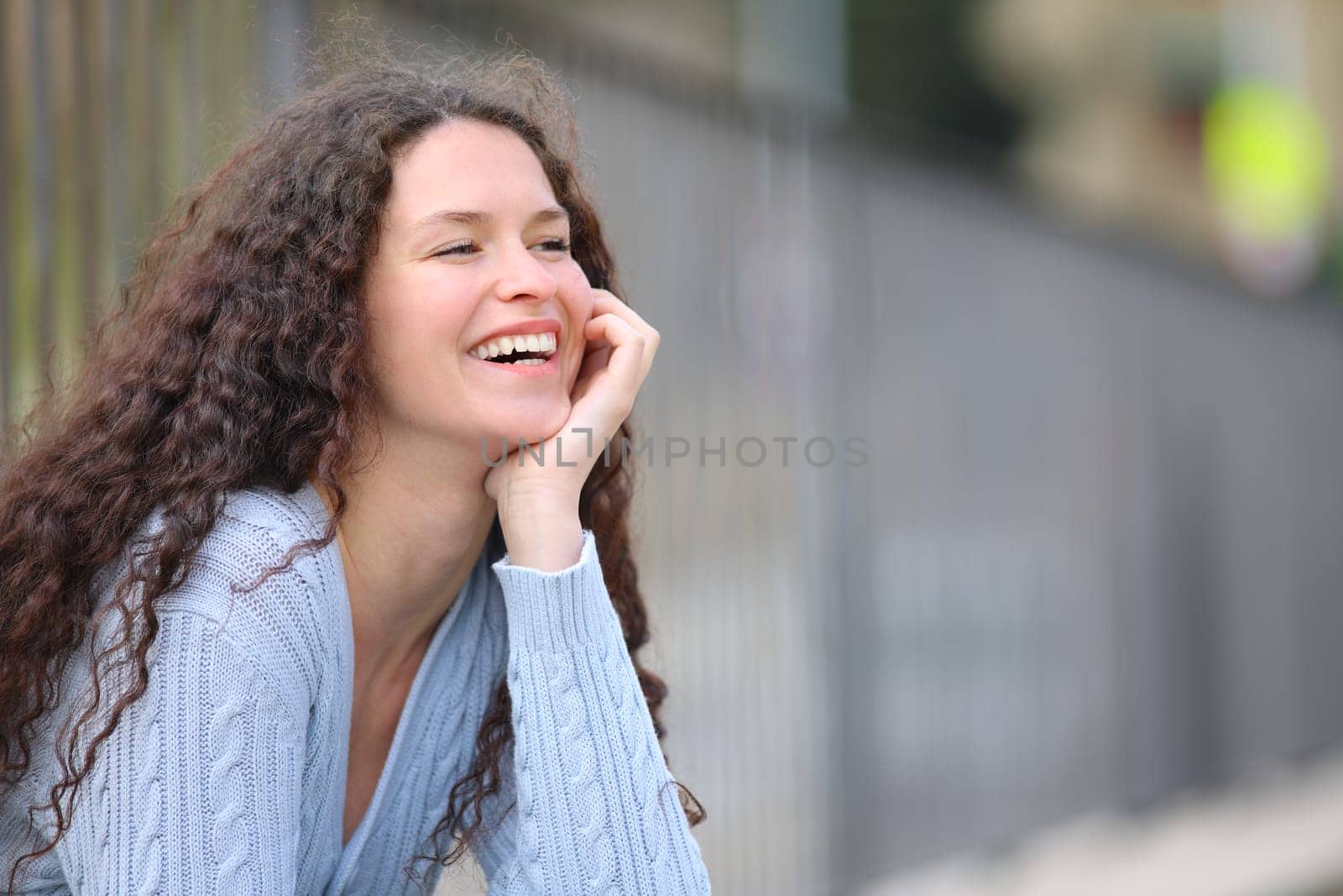 Happy woman laughing sitting in the street