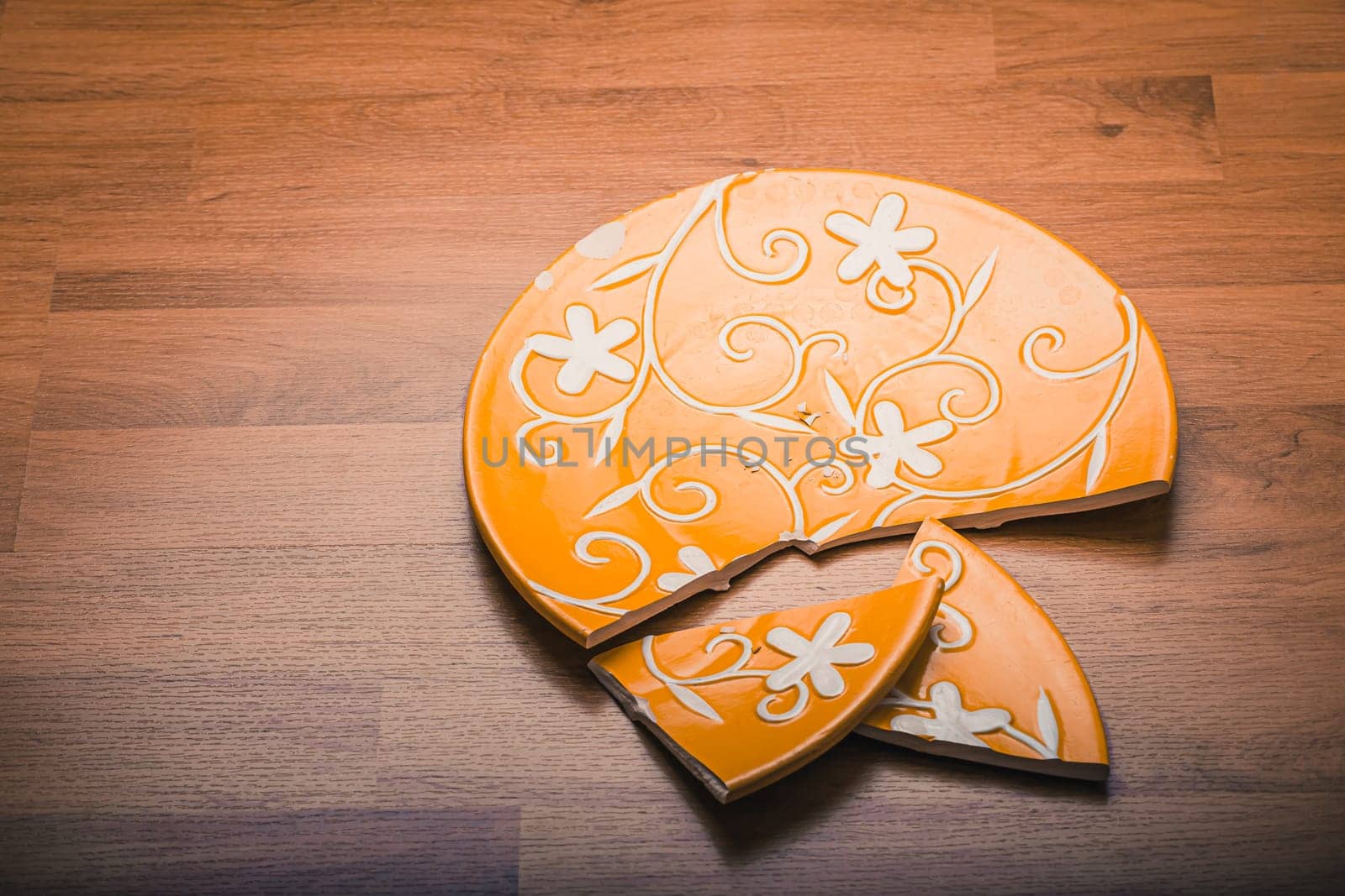 Broken ceramic plate on wooden floor