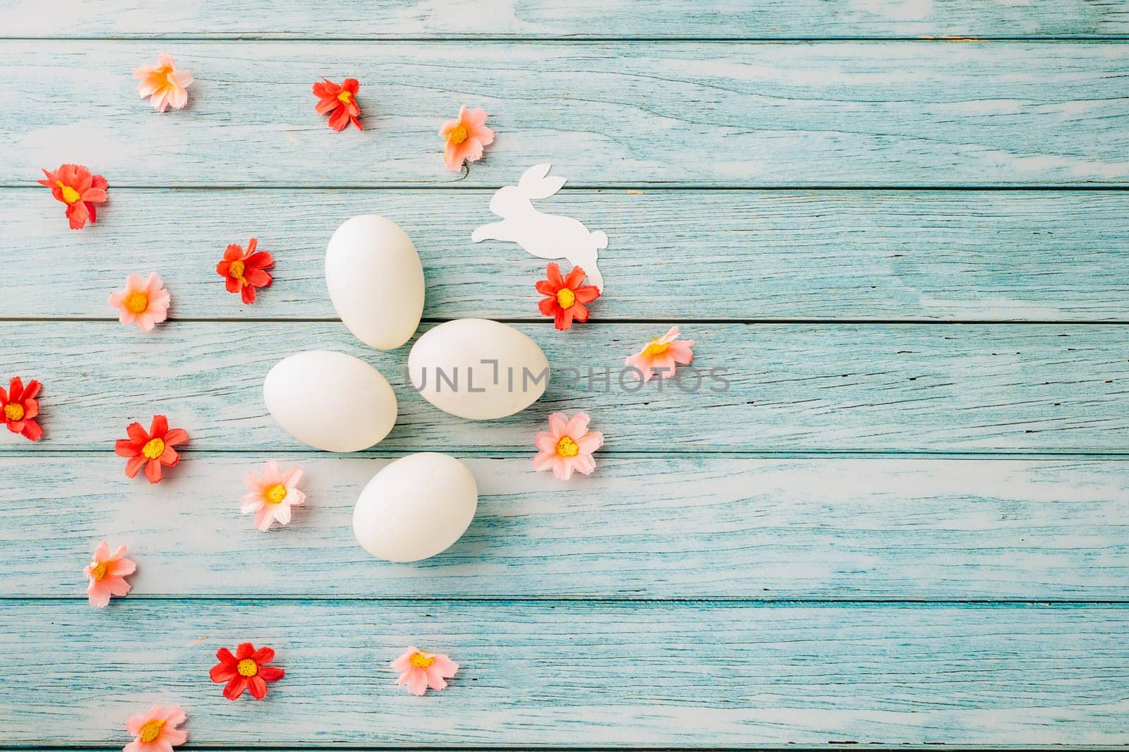 Happy Easter Day Concept. Top view of holiday banner background design white easter eggs and spring flowers on blue wooden background with empty copy space, celebration greeting card