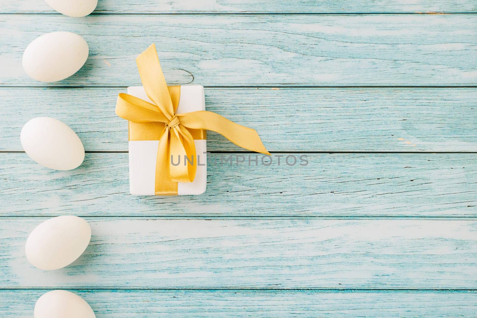 Happy Easter Day. Top view holiday banner background design with white easter eggs and gift box on blue wooden background with copy space, celebration greeting card