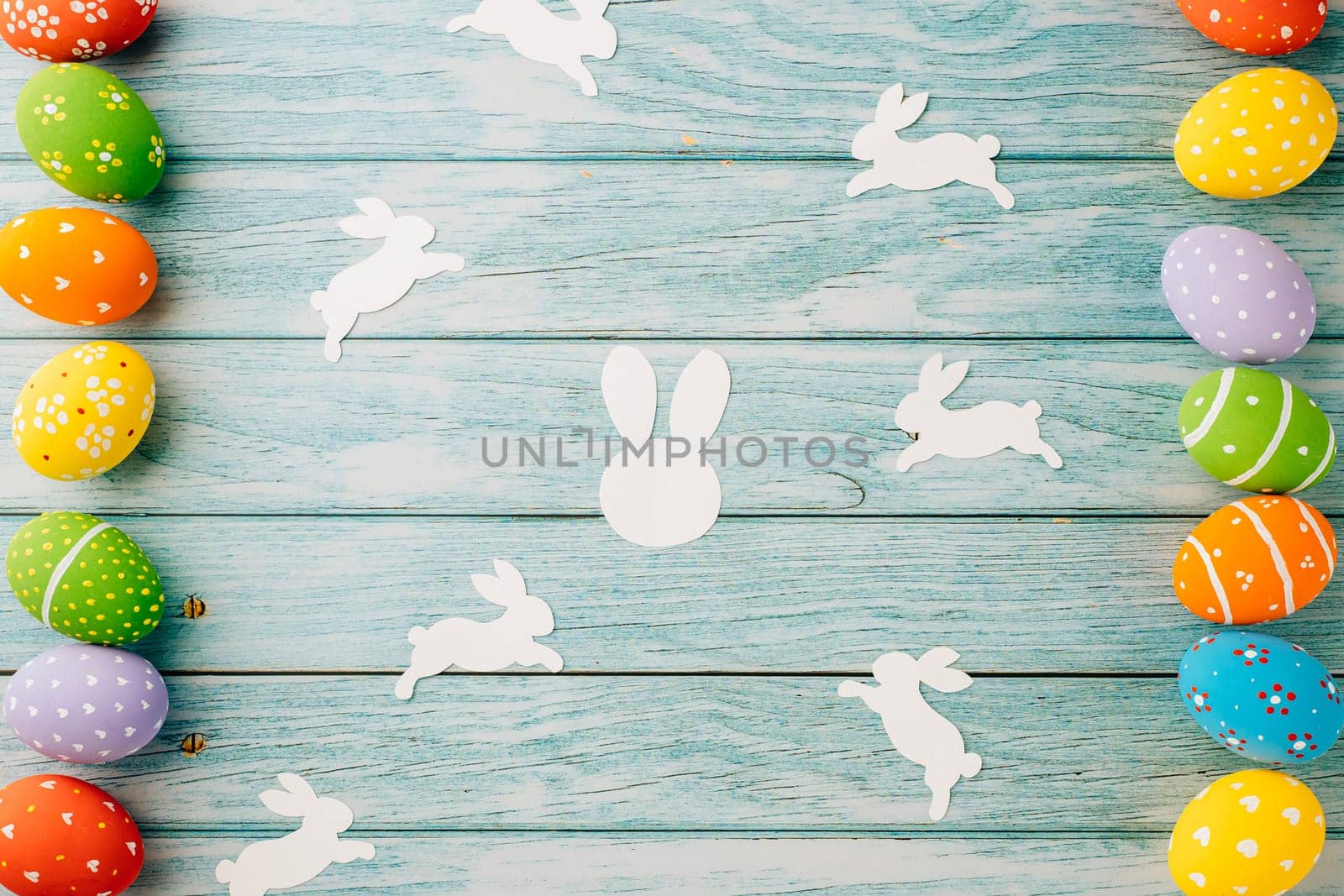 Easter Day Concept. Top view holiday banner background web design white colorful easter eggs and paper bunny rabbit on blue wood background with copy space, celebration greeting, overhead, template