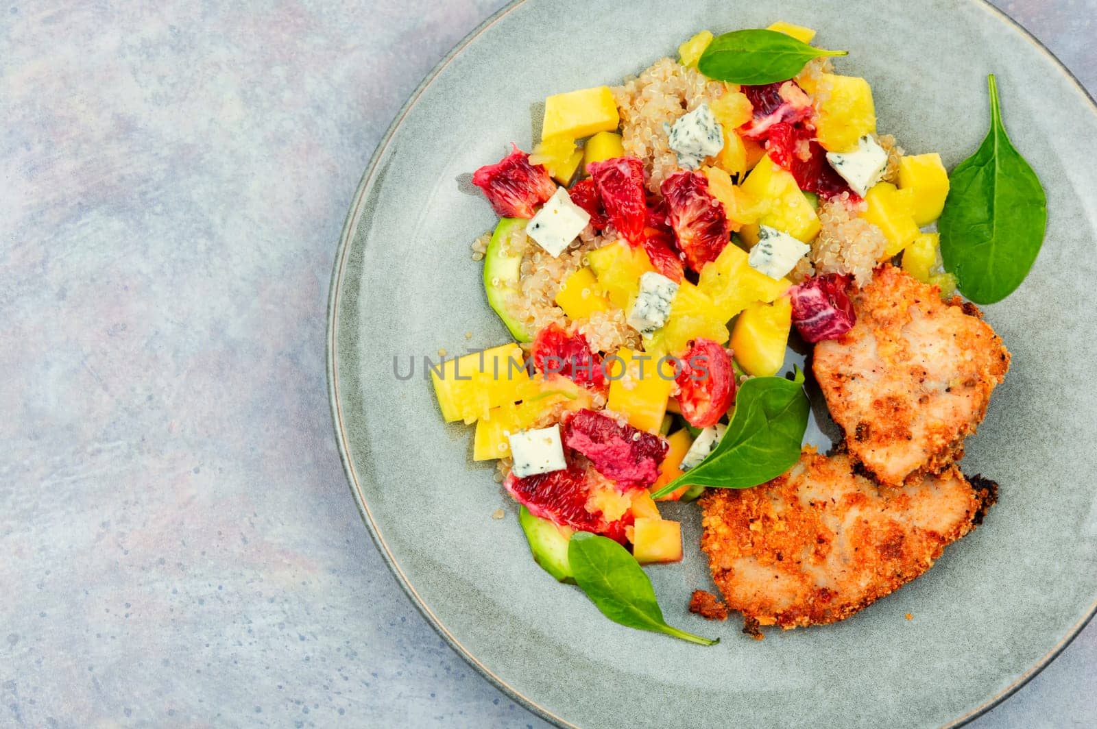 Appetizing salad with chicken meat, orange, mango and quinoa