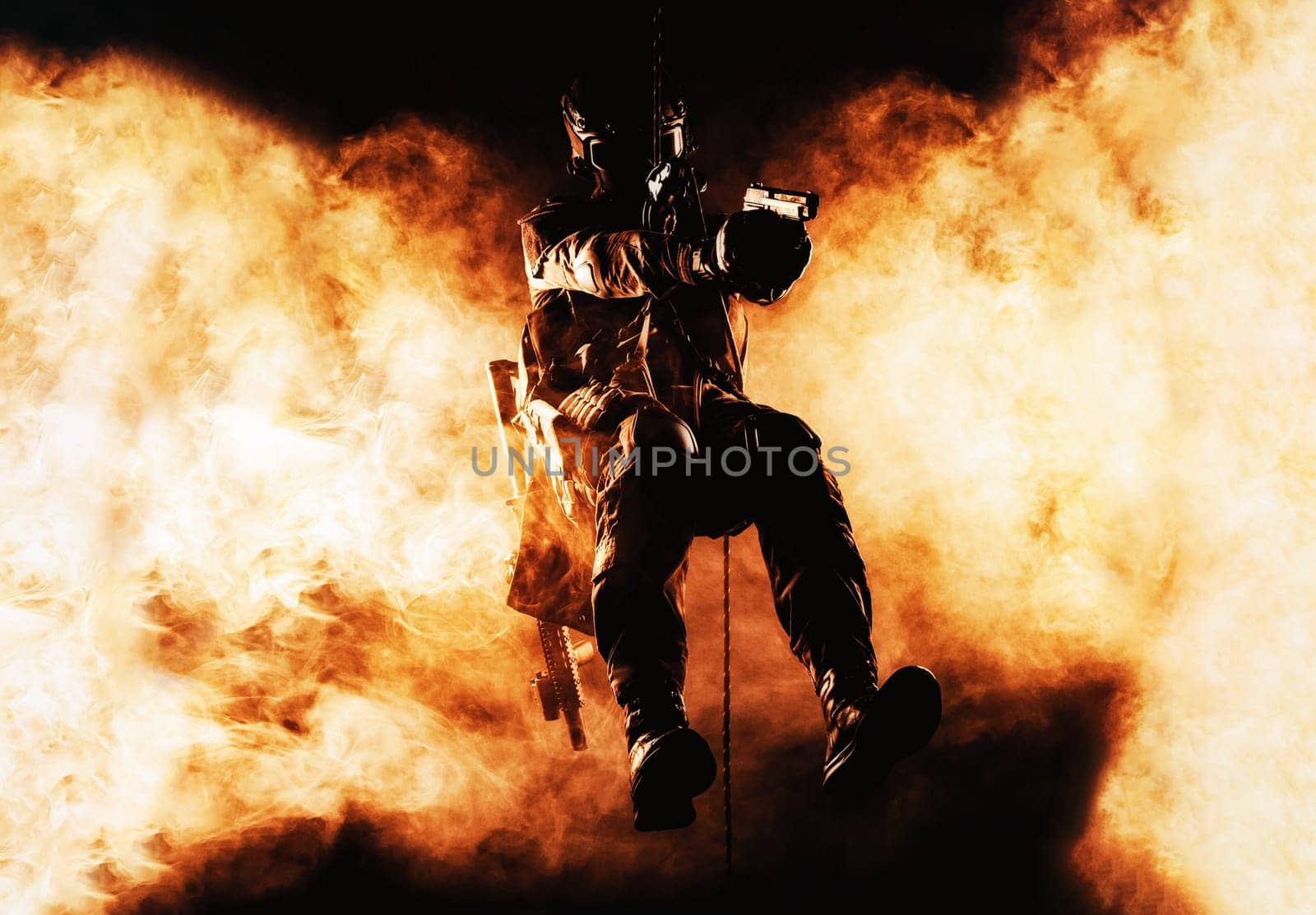 Silhouette of police officer in tactical gear descending from a height, rope exercises with weapons. Tactical rappelling, anti-terror or counter terrorism operation in darkness in rappelling harness