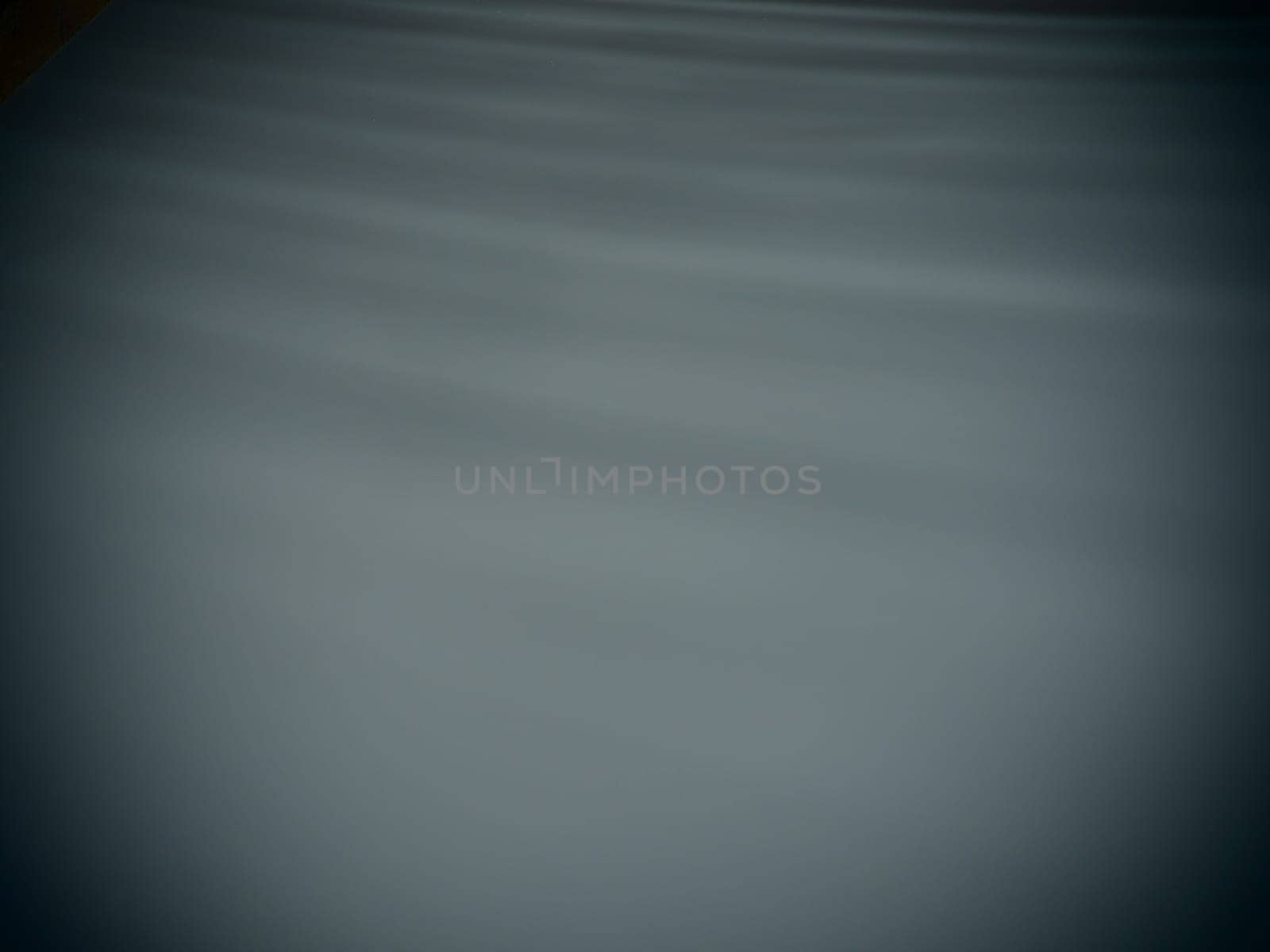 Diagonal rays of light on a gray background. Blurred abstract background light effect, light leaks. Side surface illumination. Small sparks and glow. Shine, glint or glare.