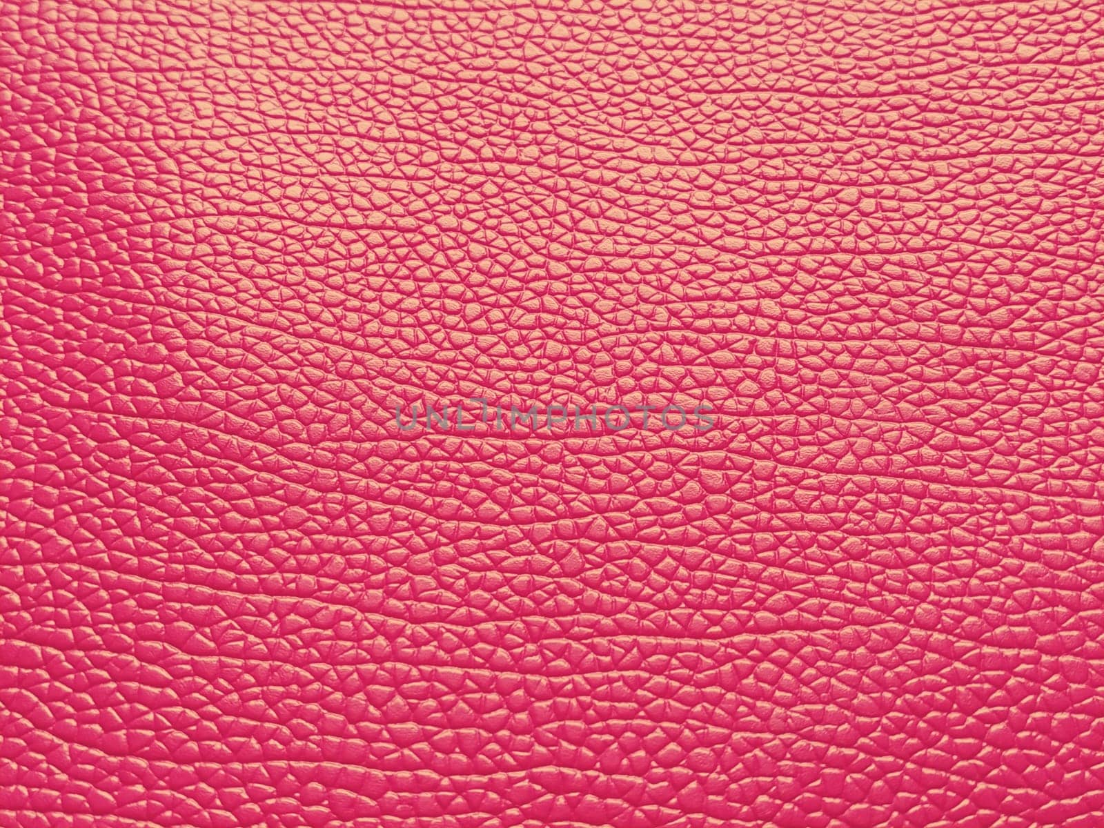 Faux leather scarlet. Separate grooves and elevations on the surface of a bag or shoe. Reflection of the light. Fashion accessory made of faux pig skin. Close-up.