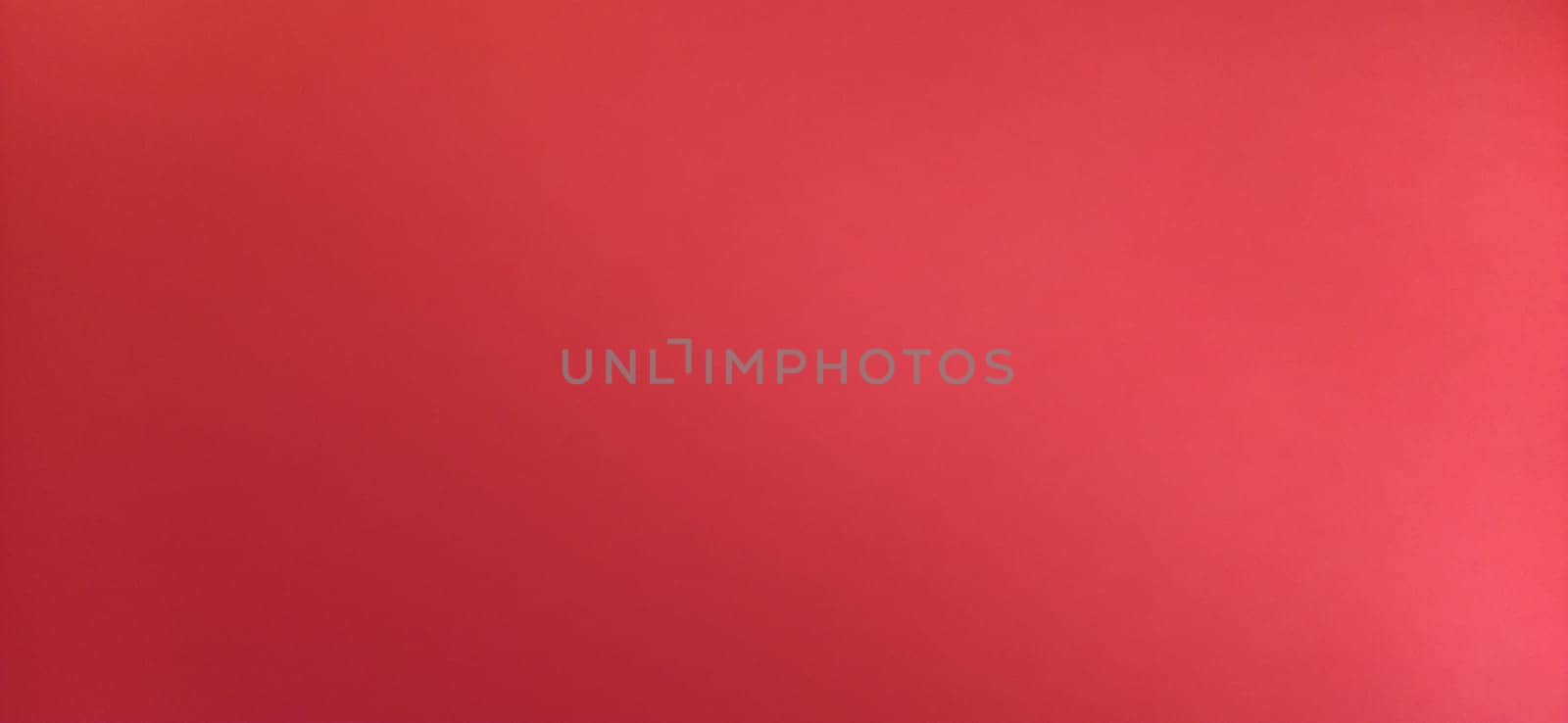 Red beautiful bright background. Color gradient depending on the light. To the left - dark red, to the right - the hue brightens. Scarlet uneven color. Sheet of colored paper with natural light