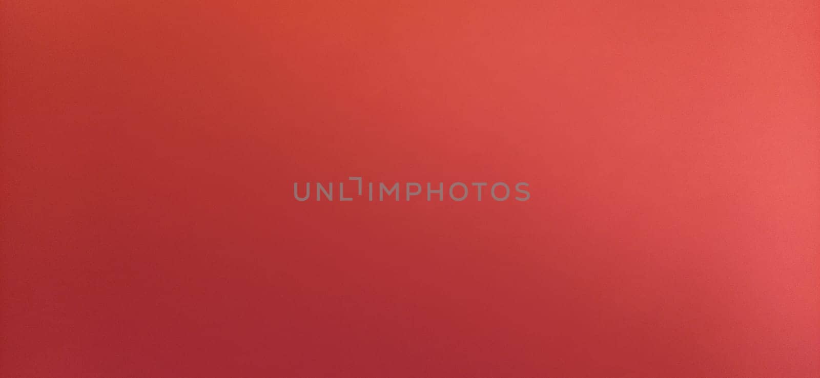 Red beautiful bright background. Color gradient depending on the light. To the left - dark red, to the right - the hue brightens. Scarlet uneven color. Sheet of colored paper with natural light.
