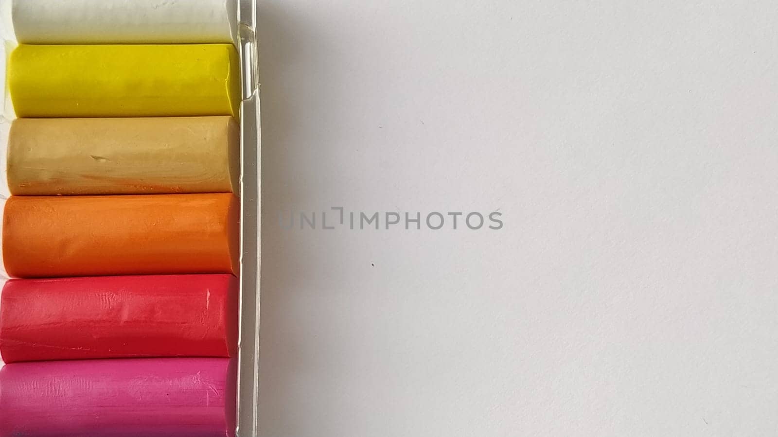 Multi-colored new plasticine in plastic packaging on a white background.