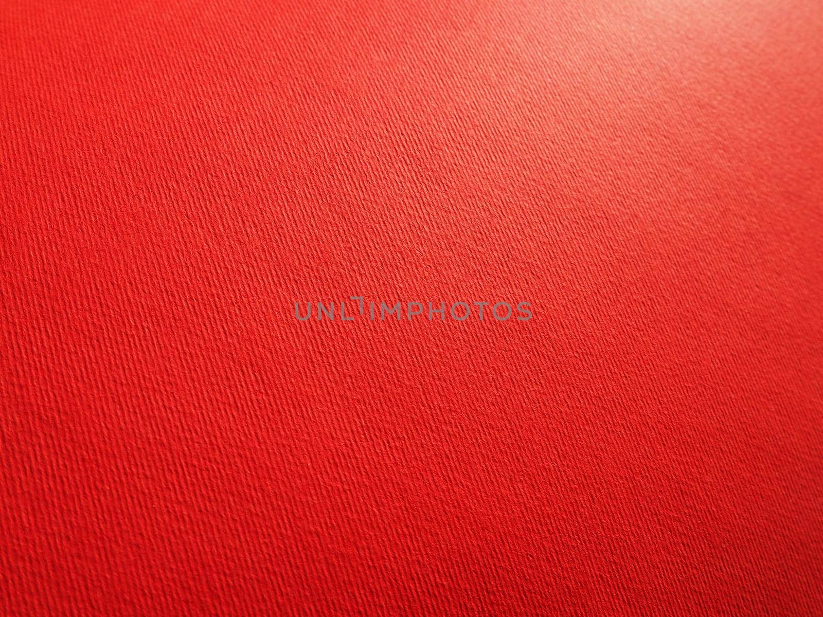 Abstract red background with texture. Close-up of paper surface with light and color gradient. Side lighting. Bright crimson backdrop.