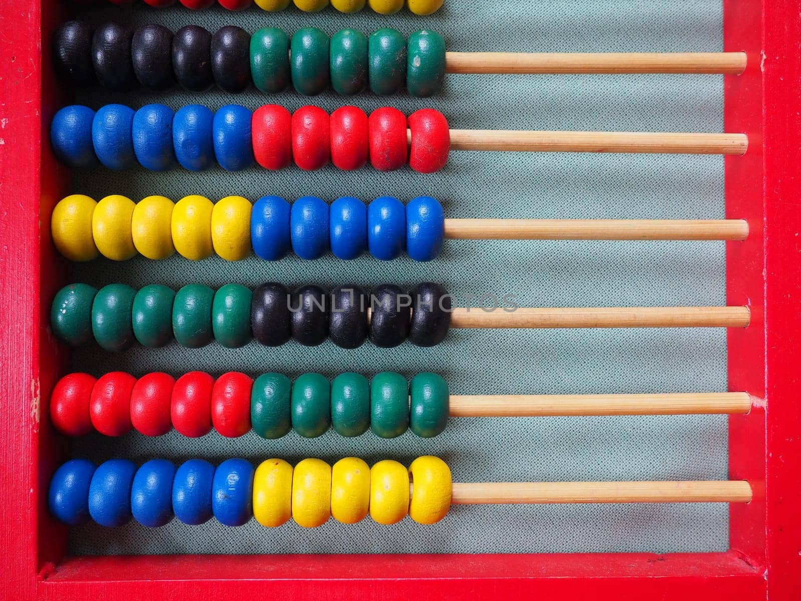 Education concept - abacus with many colorful beads. Red, blue, green, black, yellow details on the abacus. Mathematical exercises. School program.