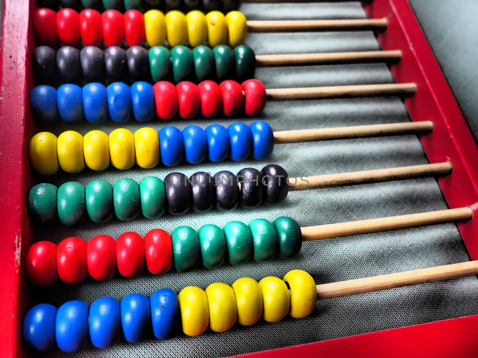 Education concept - abacus with many colorful beads. Red, blue, green, black, yellow details on the abacus. Mathematical exercises. School program.