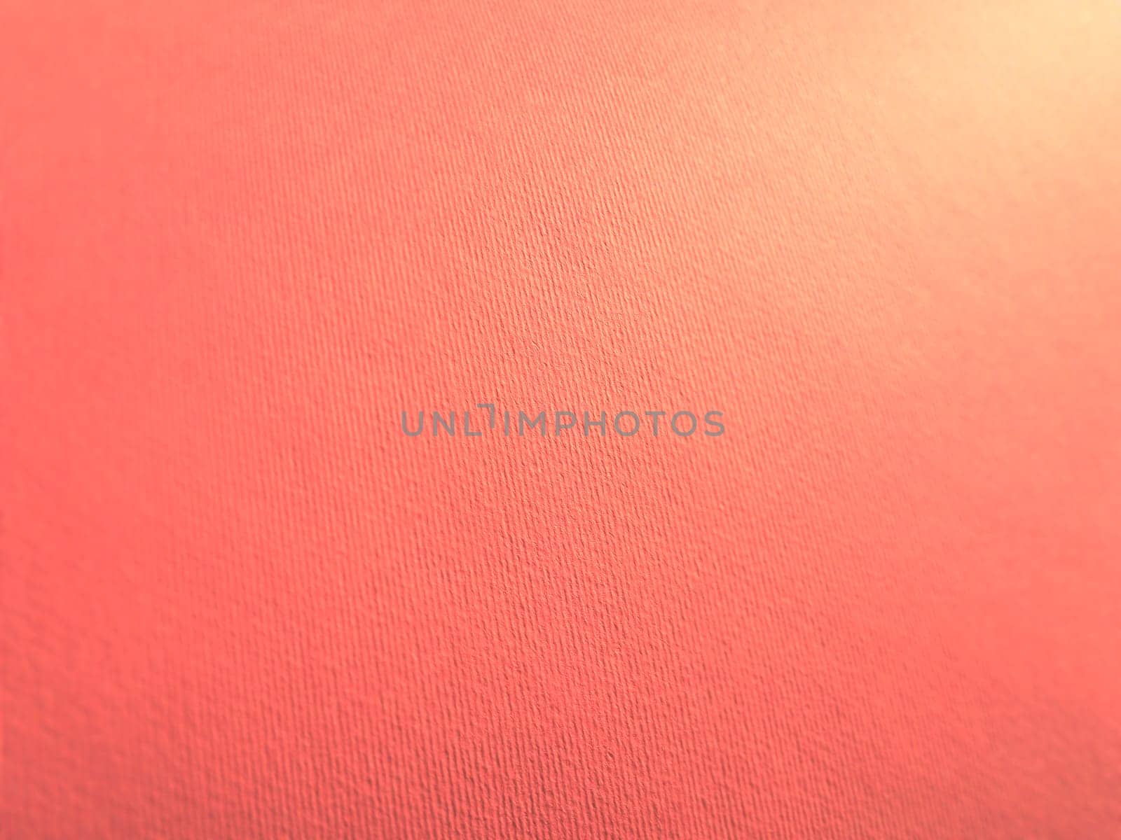 Abstract pink background with texture. Close-up of paper surface with light and color gradient. Side lighting. Soft pastel peach or ruddy tone backdrop