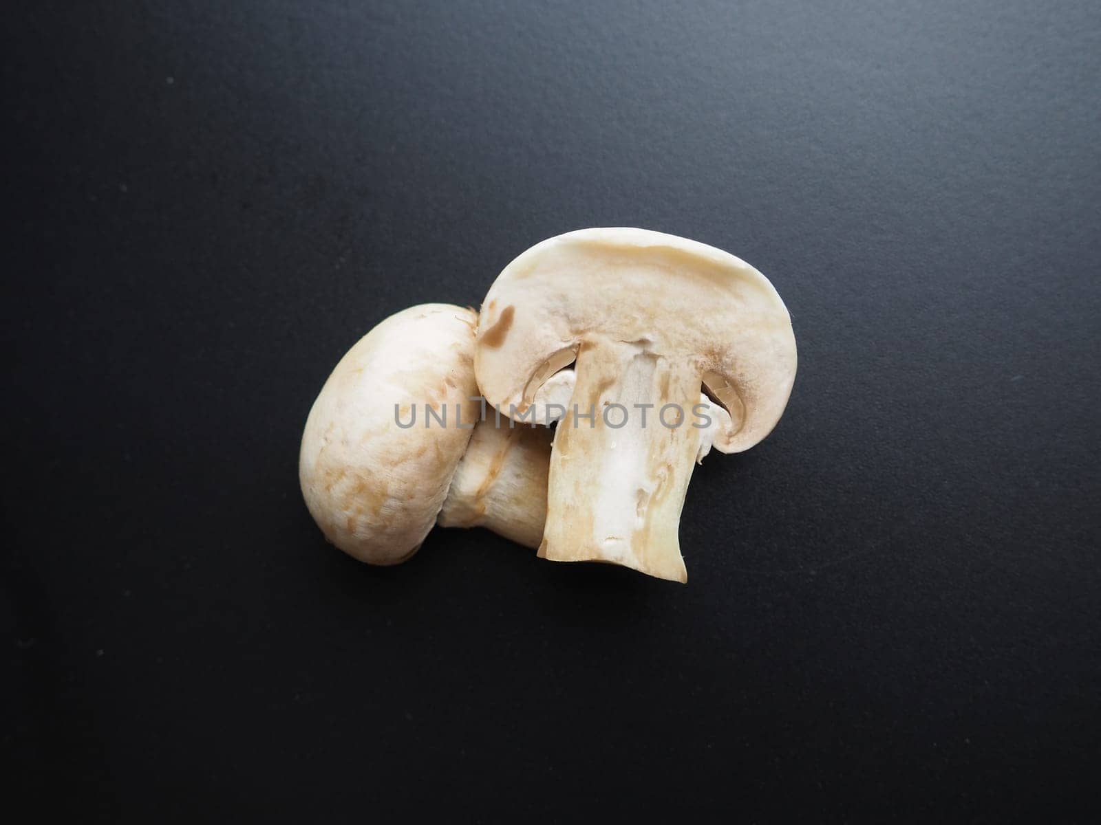 Champignons on a black background. Sliced and whole fresh uncooked raw mushrooms. Cooking mushrooms with a recipe