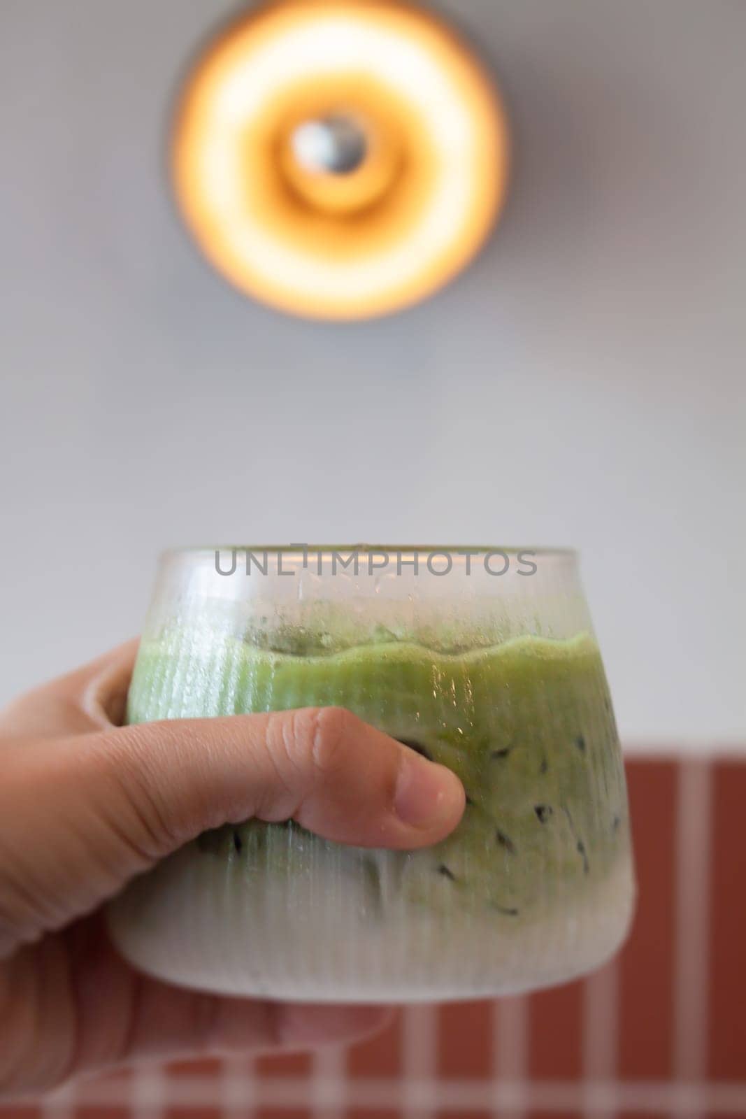 Hand holding iced matcha green tea, stock photo
