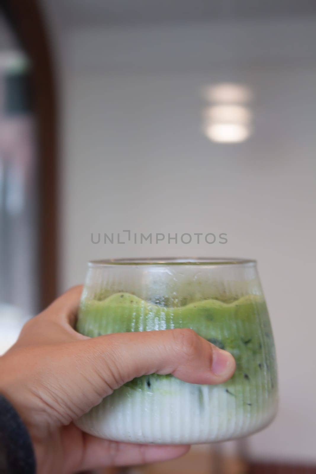 Hand holding iced matcha green tea, stock photo