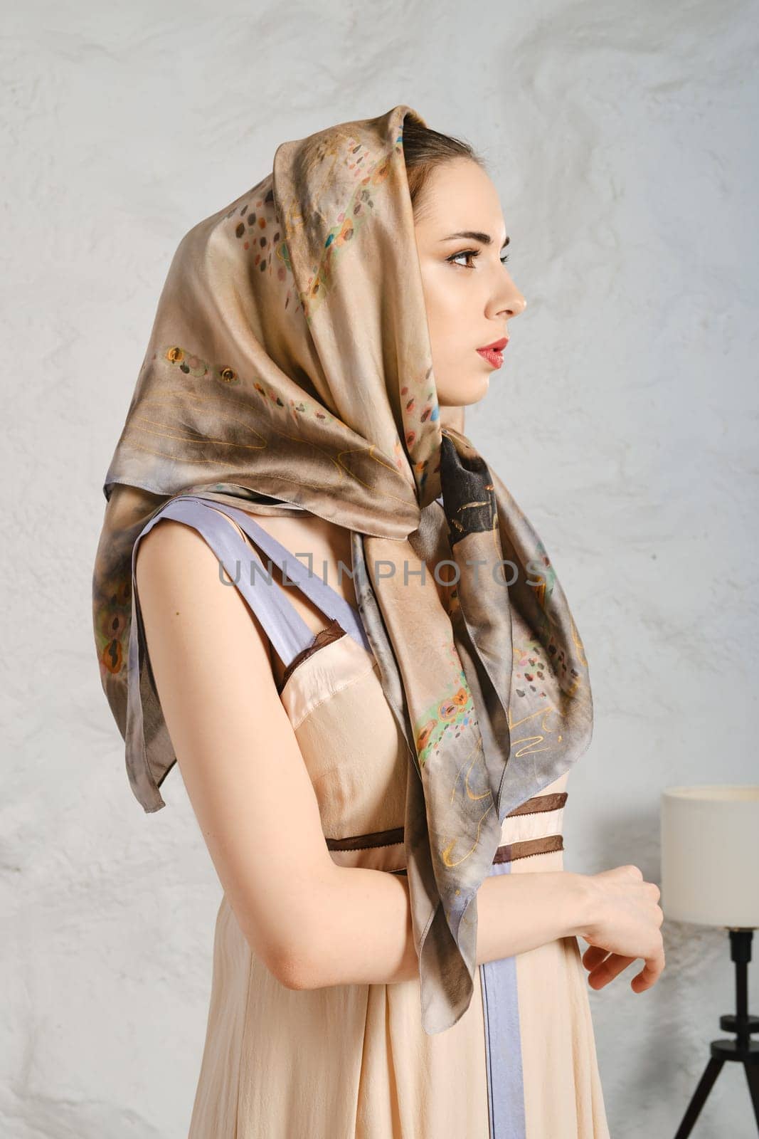 Young woman with silk scarf on her head standing in profile