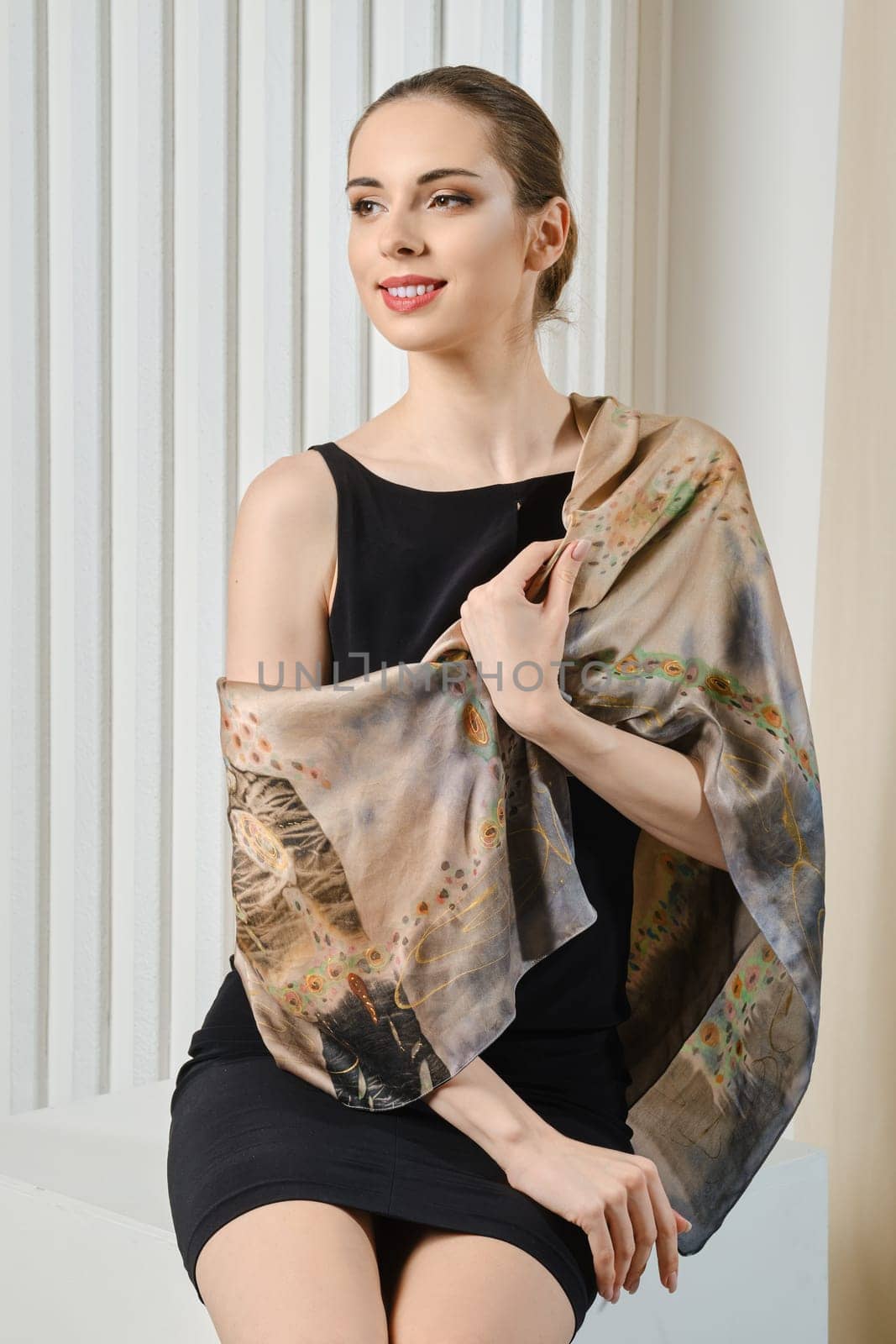 Beautiful woman in black dress with silk scarf over one shoulder looking straight