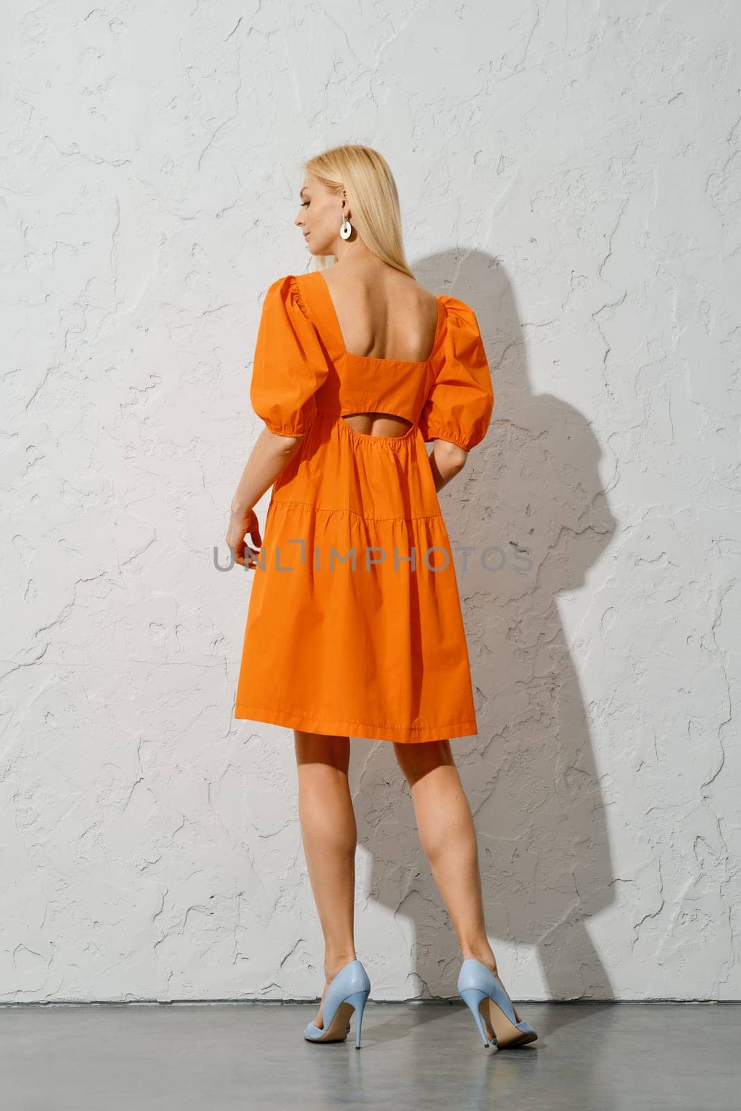 Back view of stylish adult woman in loose orange dress