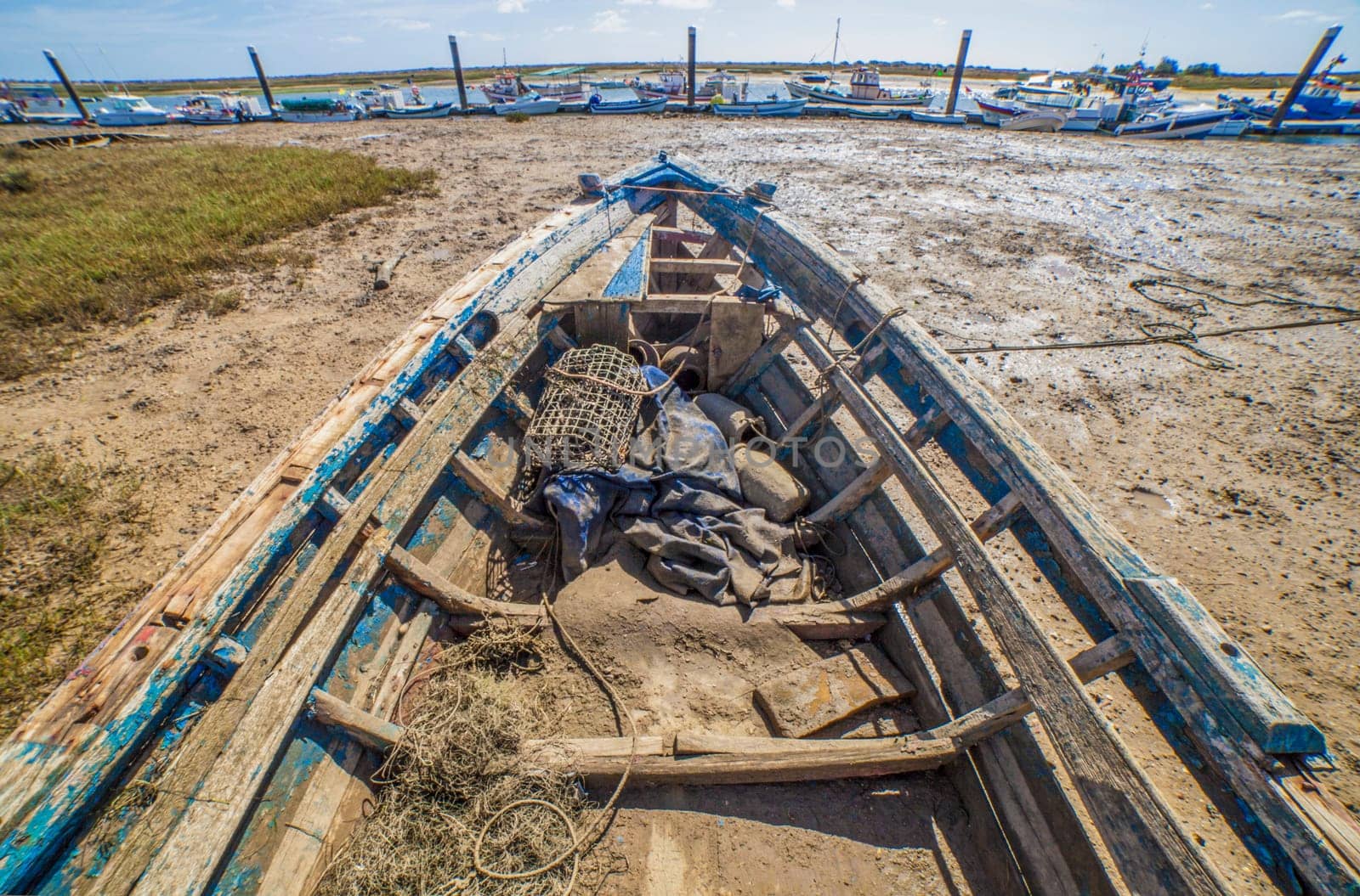 Old wooden fishing boat docked in low tide sand. Cabanas de Tavira, Portugal