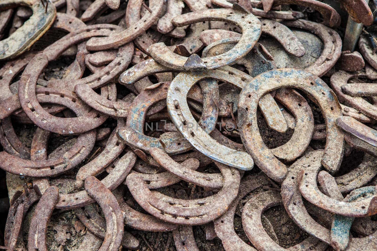 Pile of old used and rusty horseshoes. Selective focus