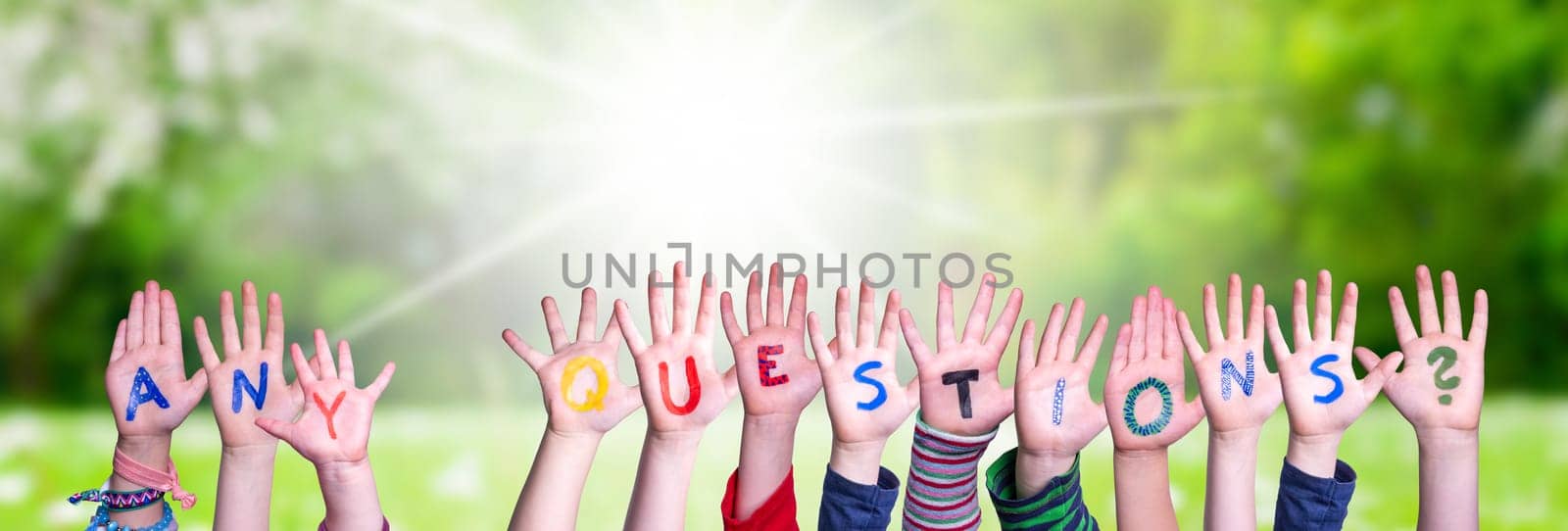 Children Hands Building Colorful English Word Any Questions. Sunny Green Grass Meadow As Background.