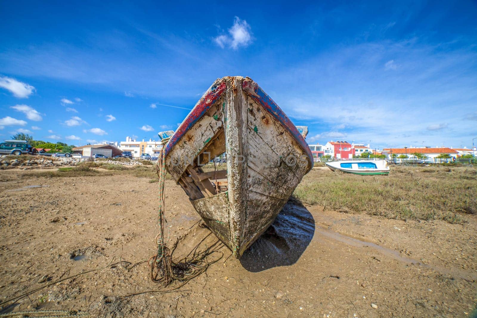Old wooden fishing boat docked in low tide sand. Cabanas de Tavira, Portugal