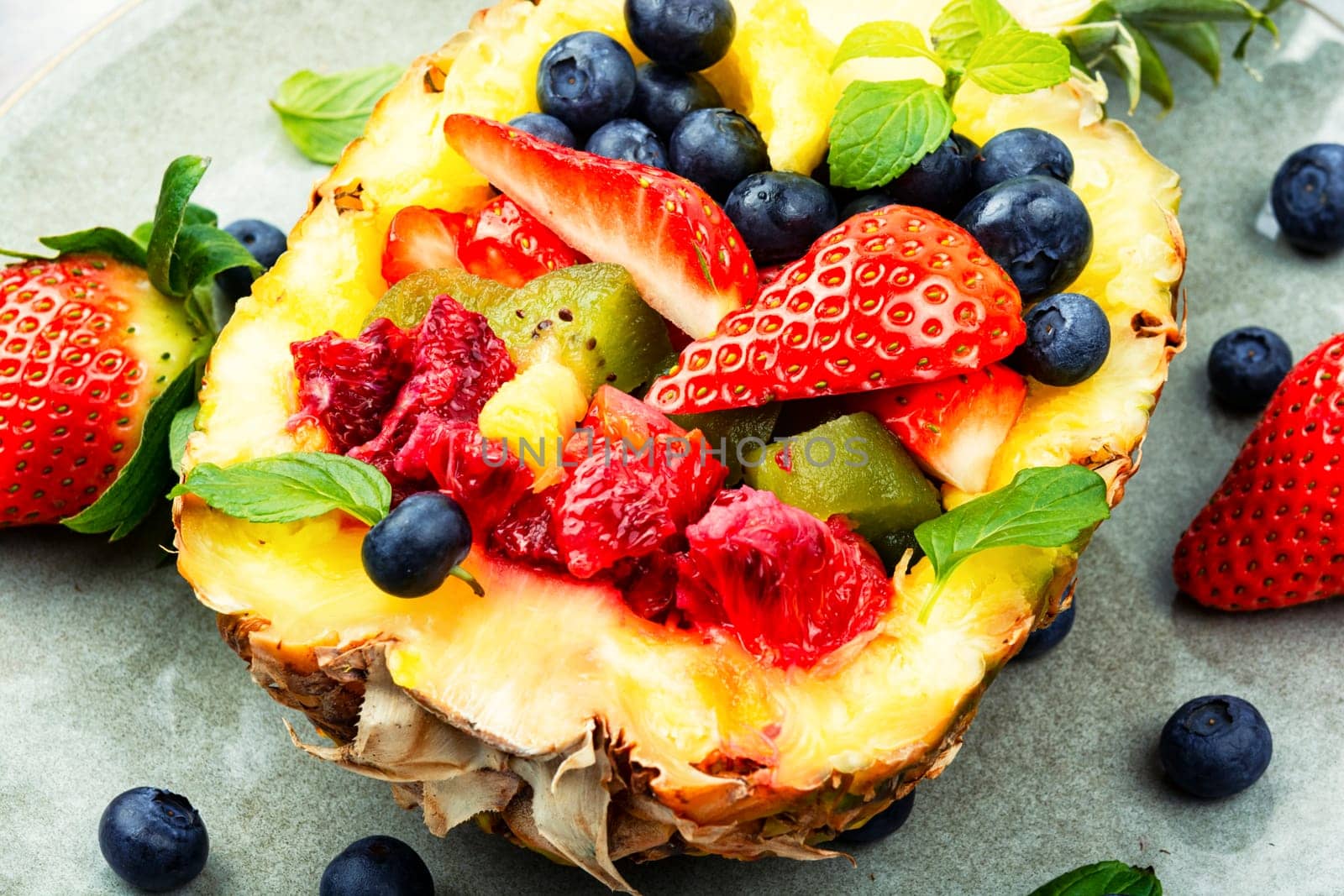 Delicious fruit salad of strawberries, kiwi, berries and orange in half a pineapple. Tropical fruit