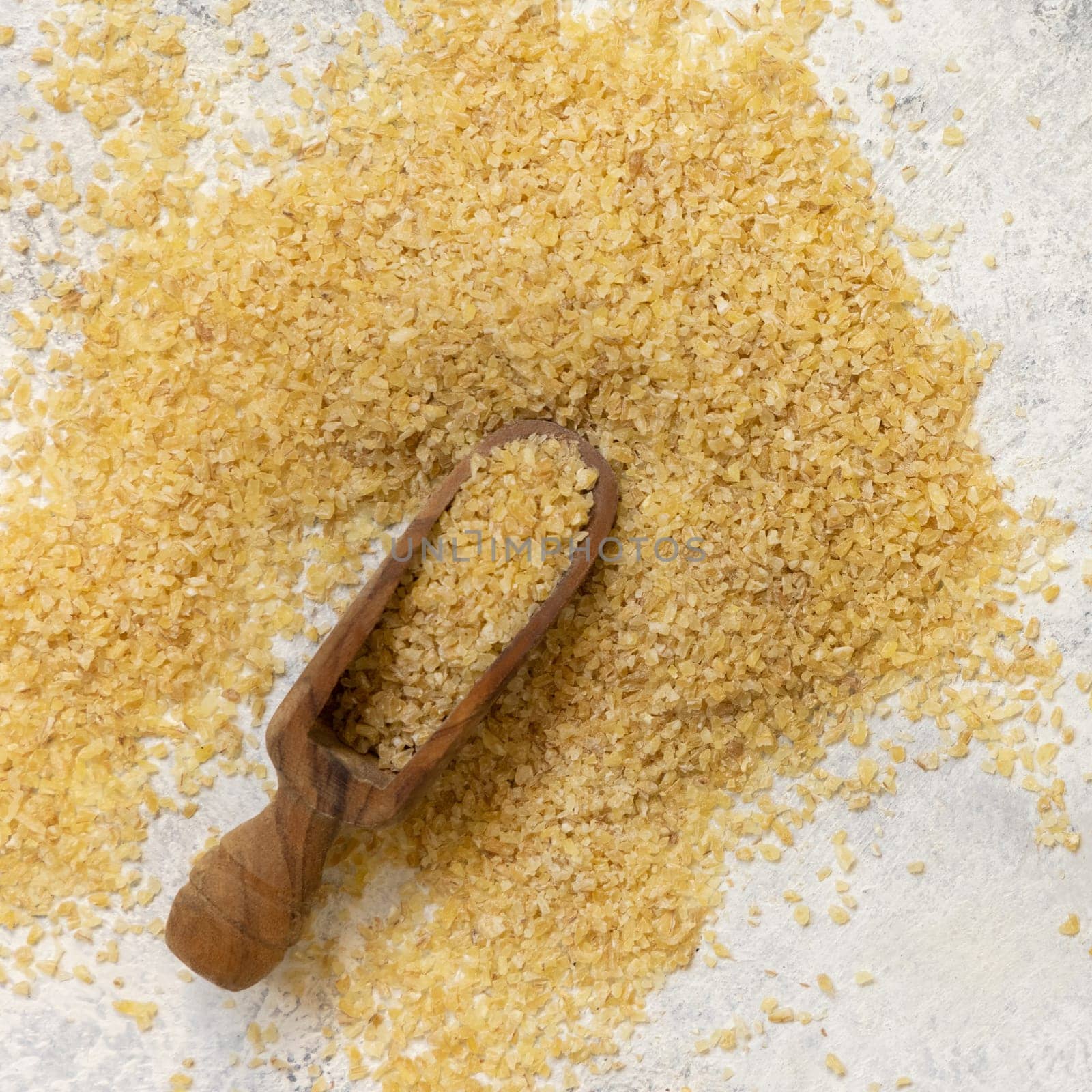 Wooden scoop of Dry uncooked bulgur wheat grain top view. Vegetarian and Vegan, Mediterranean and Middle Eastern cuisine. Healthy lifestyle