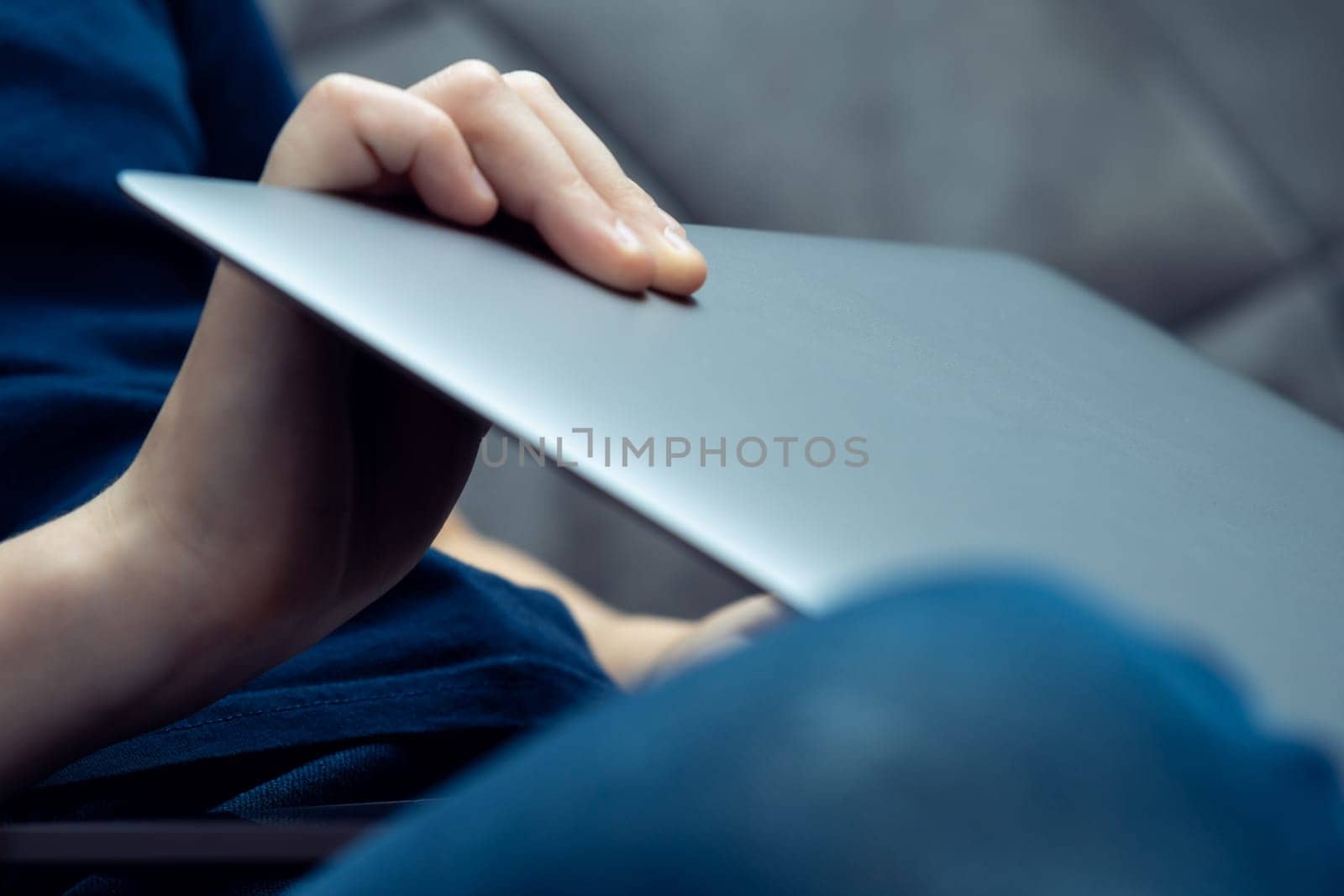 Digital laptop computer in male hands, side view closeup. Young business man close gray metal lid of portable notebook. Working on multitasking gadget, high technology, electronics.