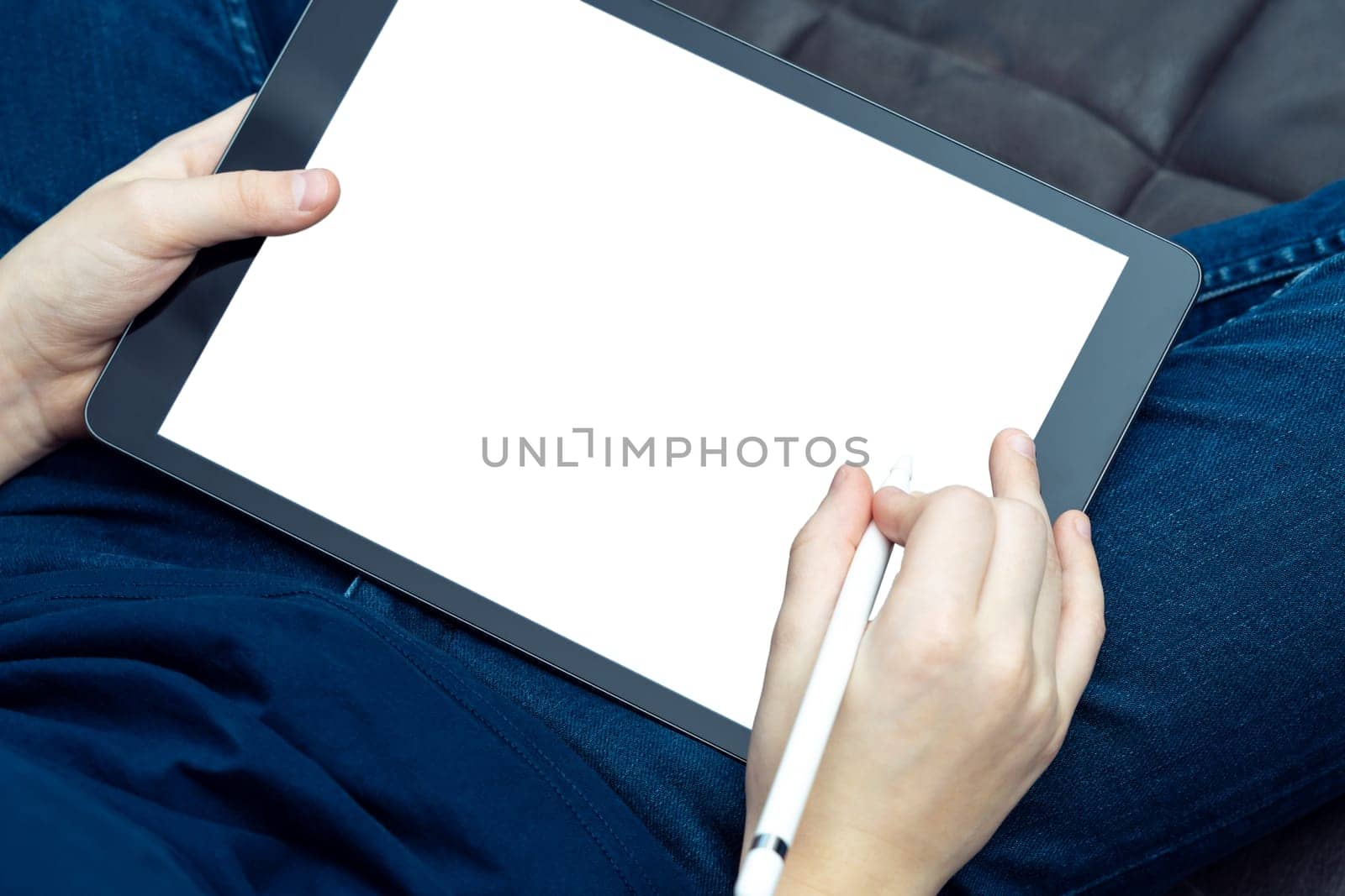 Digital tablet computer with blank white screen in male hands, from above view closeup. Business man working on modern handheld gadget with stylus. Sensory pen drawing, touchscreen, electronics.