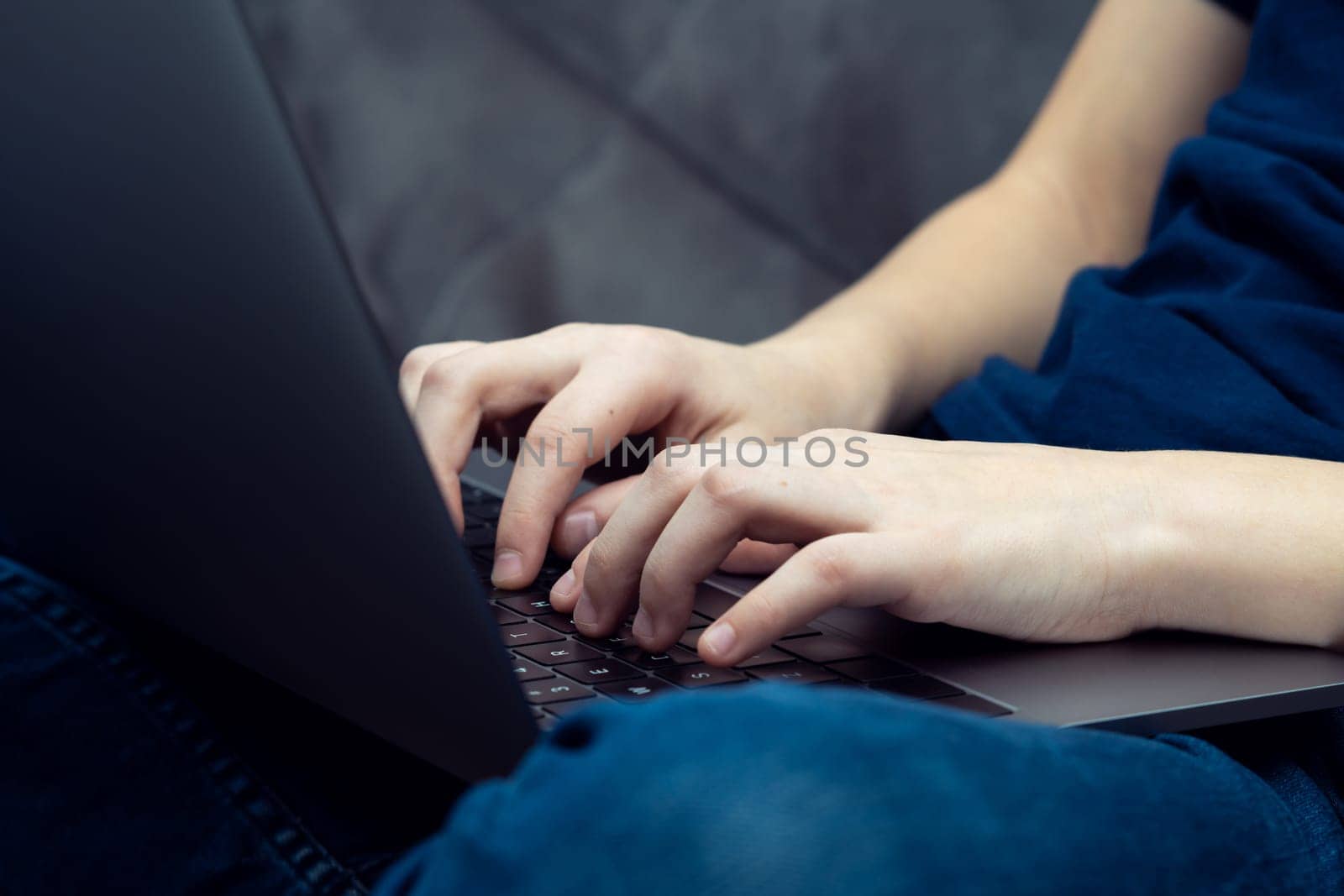 Digital laptop computer on male legs closeup. Young business man typing on keyboard of portable modern notebook. Working on multitasking gadget, high technology, IT sphere, electronics.