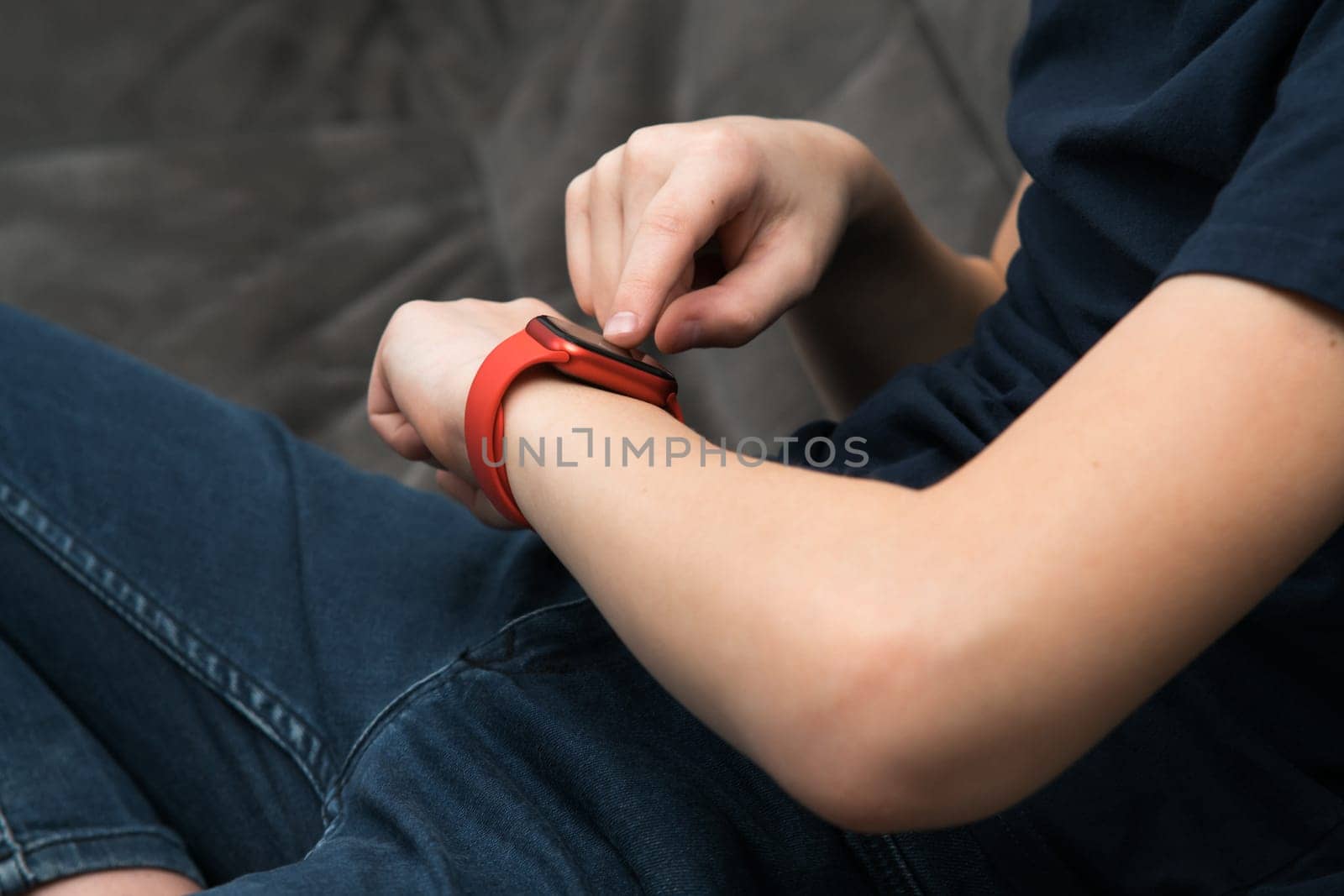 Red stylish smart watch on male wrist, side view closeup. Young business man touch finger on screen of wearable gadget and look time and data. Multitasking watch, touchscreen, modern electronics.