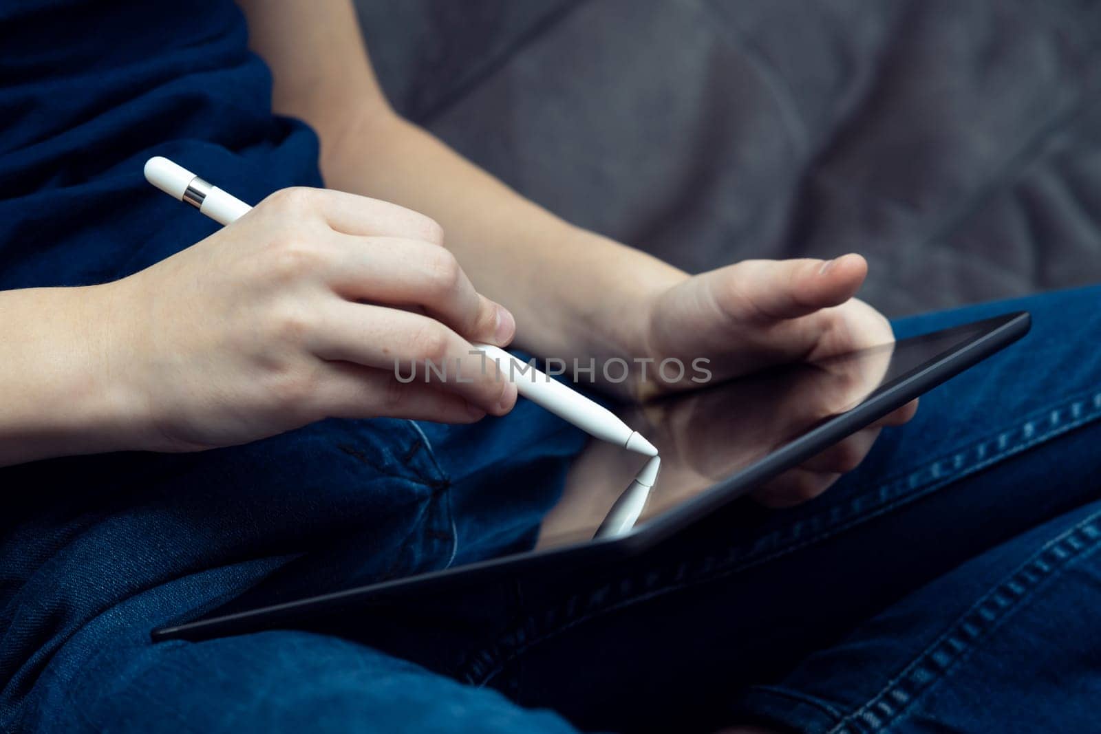 Digital tablet computer in male hands, side view closeup. Young business man work on multitasking handheld gadget with stylus. Sensory pen drawing and writing, touchscreen, electronics.