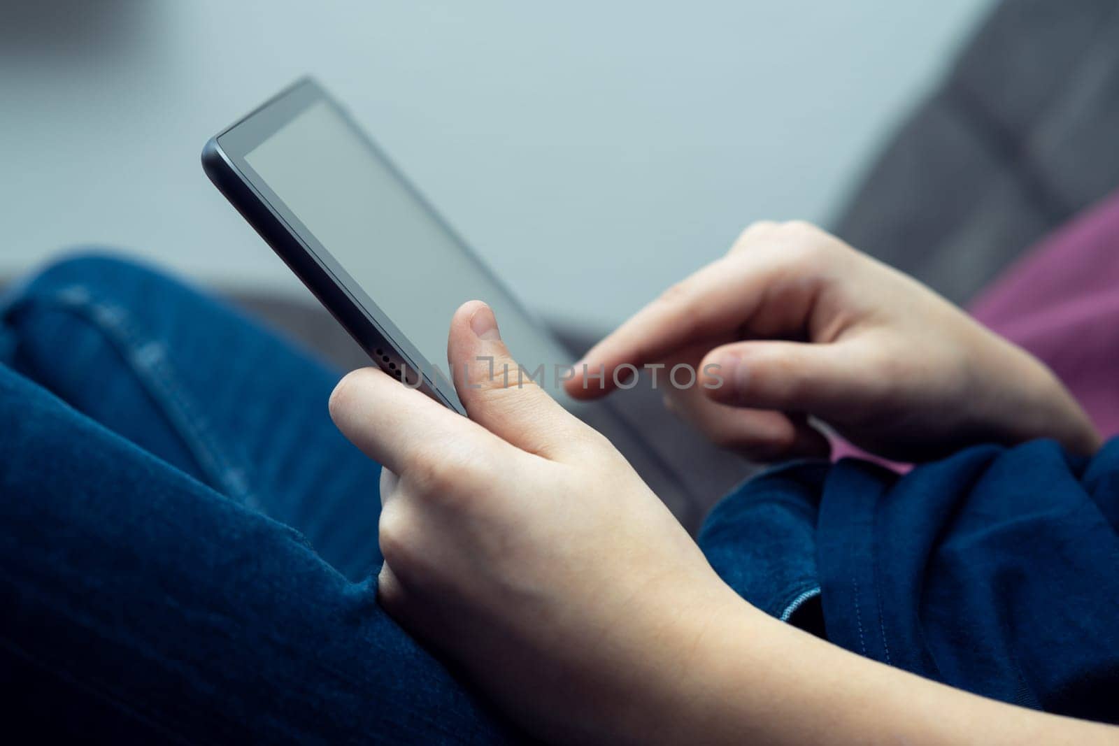 Digital tablet computer in male hands, side view closeup. Young guy working and typing on multitasking handheld gadget. Modern technology, tablet in hands, touchscreen, electronics.